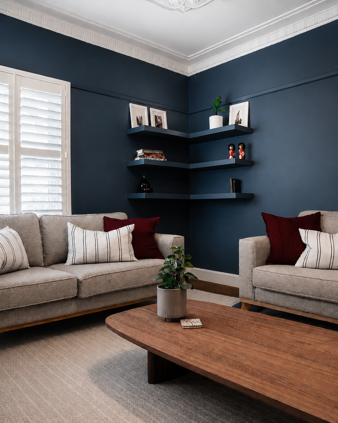 Navy blue lounge room with original ceiling rose, plantation shutters and floating corner shelving, Yarraville renovation by Lúrae Studio