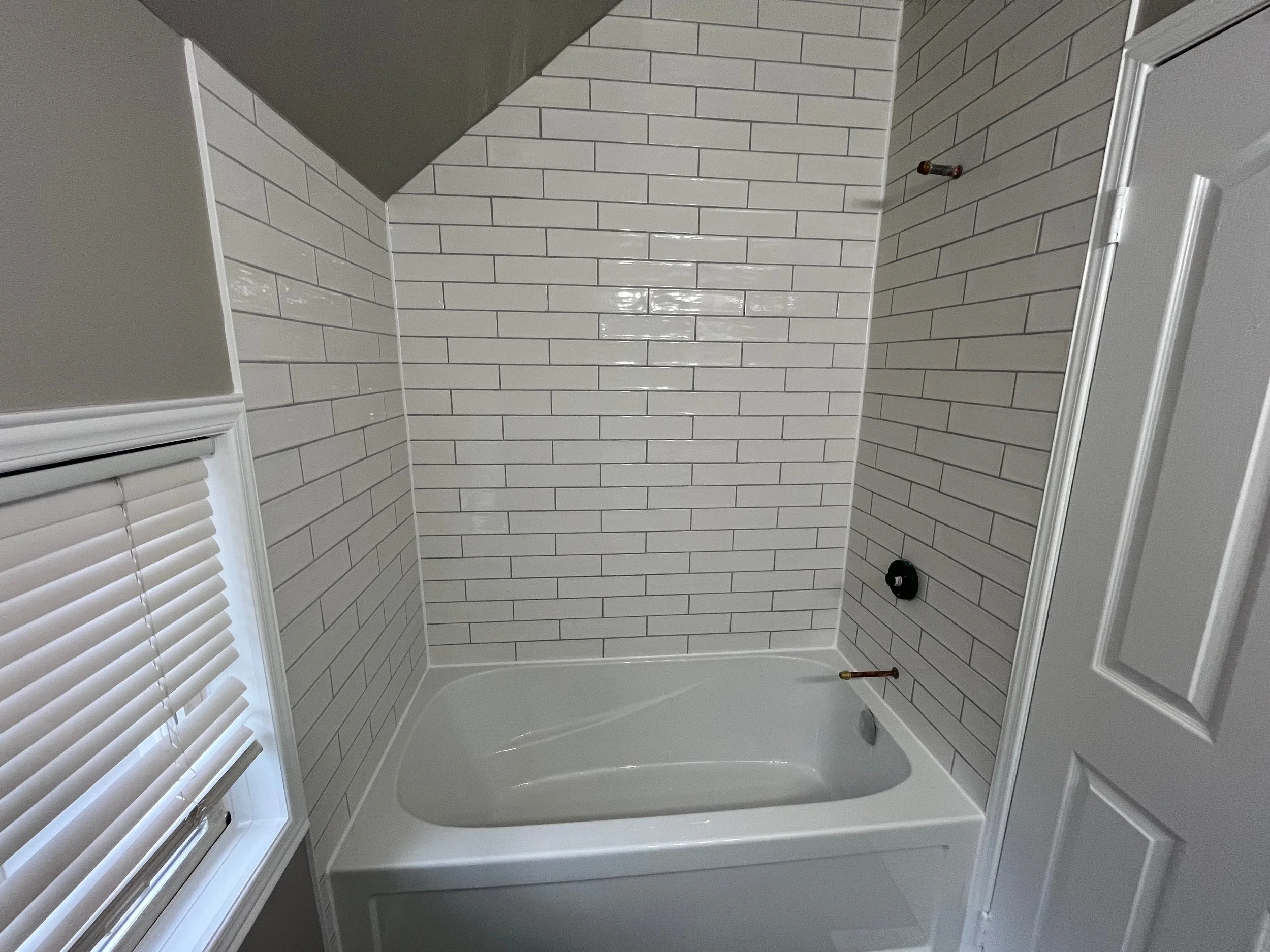 Bathroom with a bathtub and white subway tile walls.