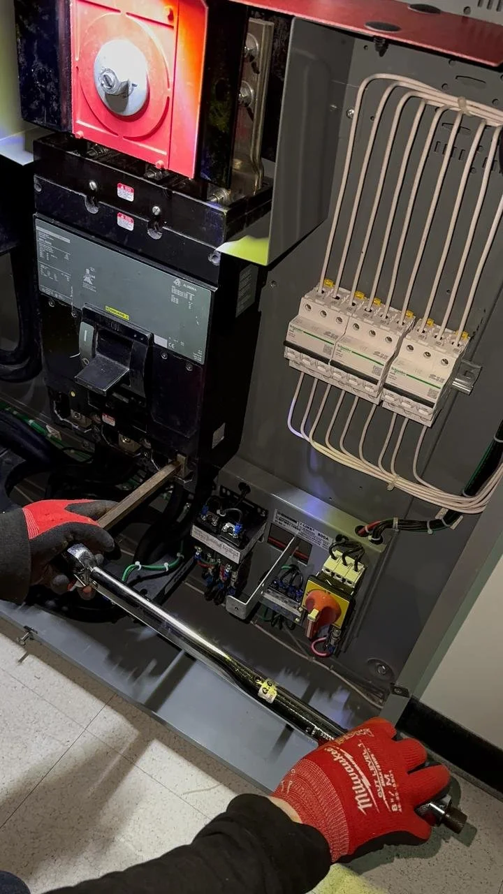 Técnico realizando mantenimiento en un panel eléctrico industrial con herramientas y componentes eléctricos.