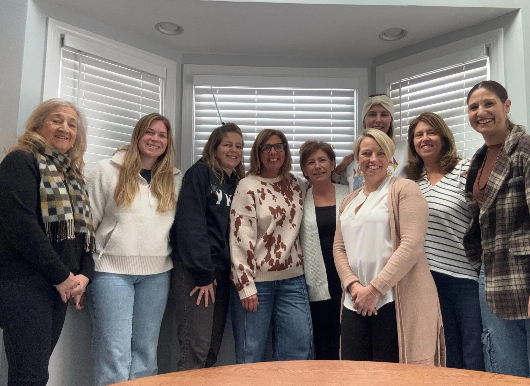 Group of ten women standing together indoors, smiling for the camera.