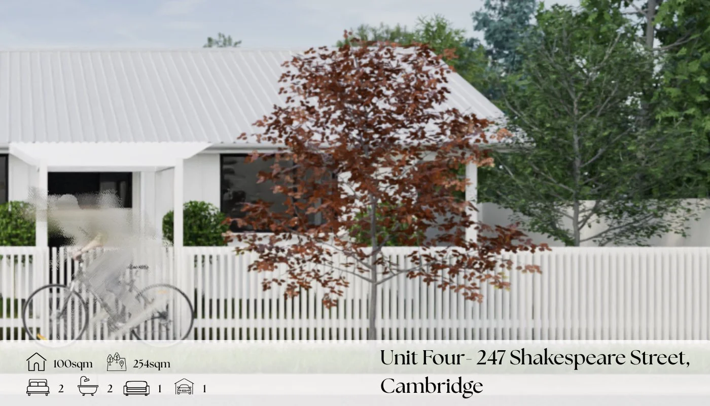 A white house with a metal roof and a front porch, surrounded by a white picket fence. In front, there is a red-leafed tree and a green tree, with a person riding a bicycle passing by.