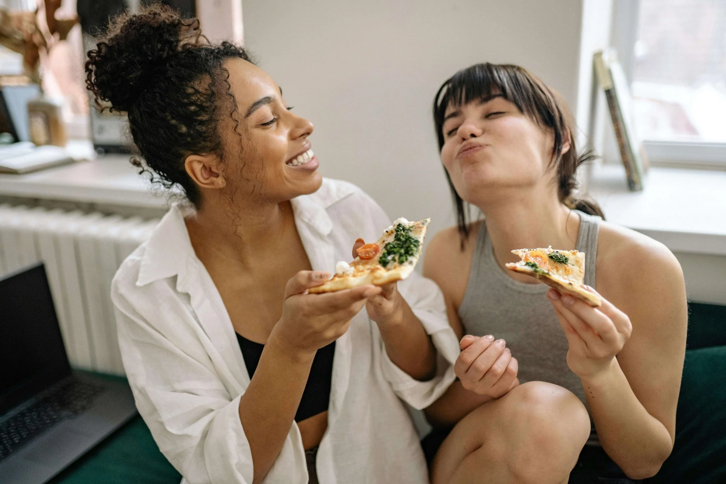healthy relationship with food friends looking at each other smiling eating pizza