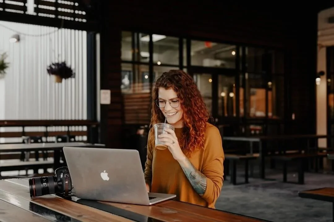 online therapy in massachusetts woman sitting at table smiling with coffee laptop open