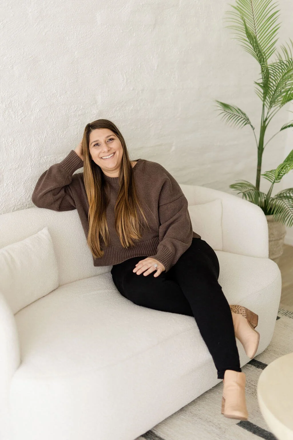natalia michaelson online california therapist with top right hand resting back of head smiling sitting on white couch
