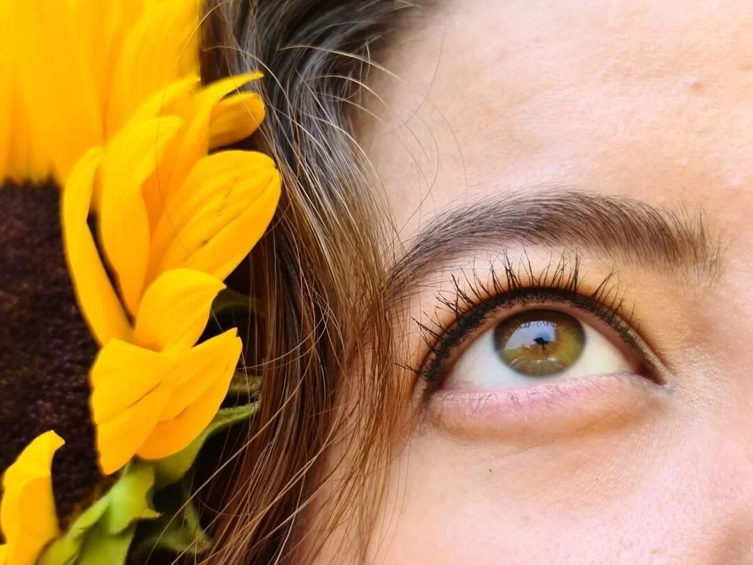orange county brainspotting hazel eye looking up with half of sunflower to the right of eye