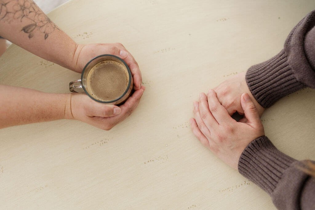 family counseling orange county set of hands cupping cup of coffee across another set of hands resting on top of one another