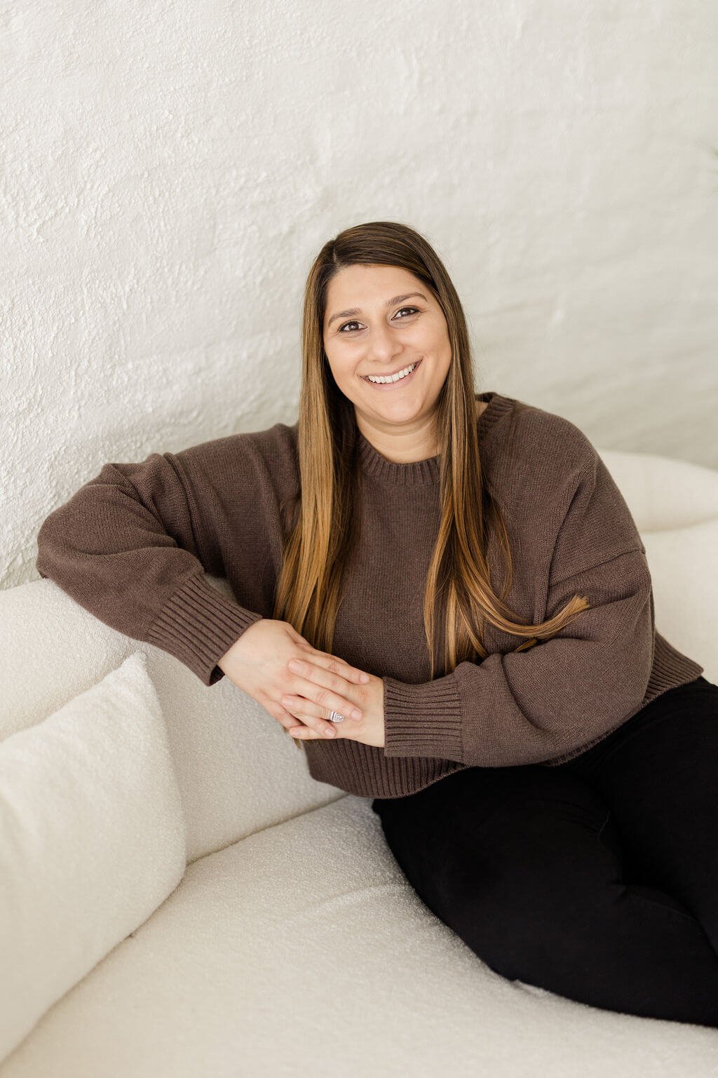 therapist in mission viejo woman brown hair brown top black pants sitting on white couch smiling