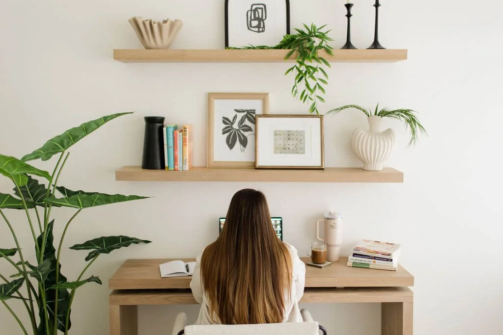 therapists ifs orange county person back looking at laptop with floating shelves books plants beige decor furniture
