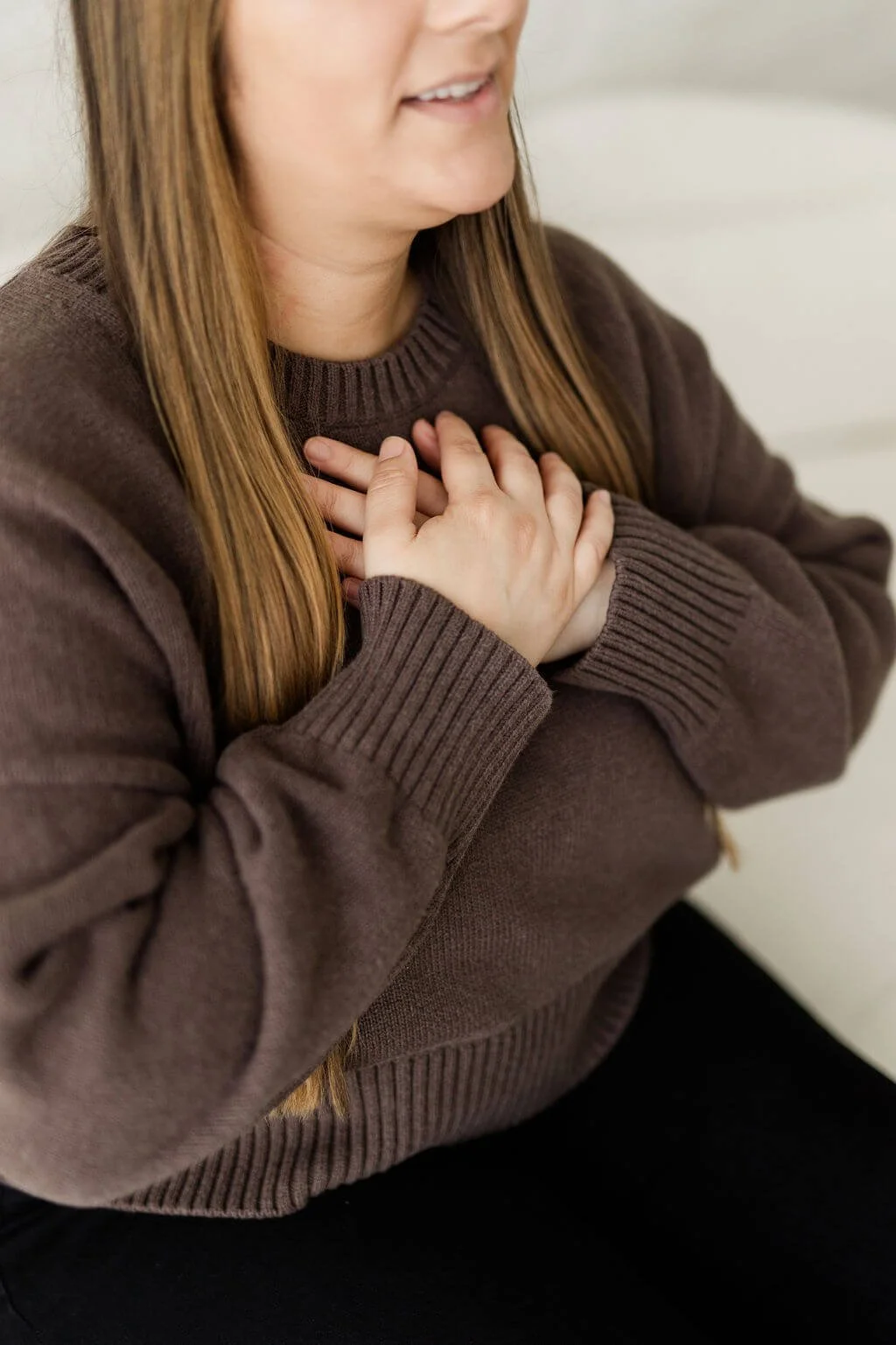 bipoc therapist orange county hands over heart resting against brown sweater