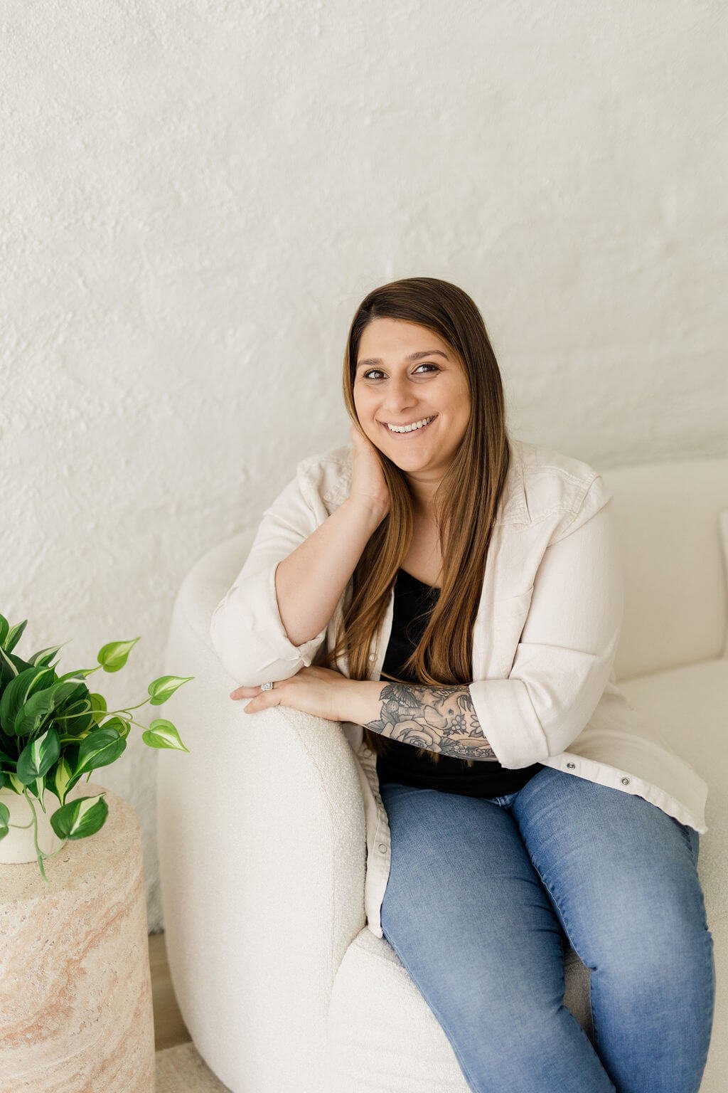 natalia michaelson boston therapist smiling right hand rested on cheek sitting on white couch