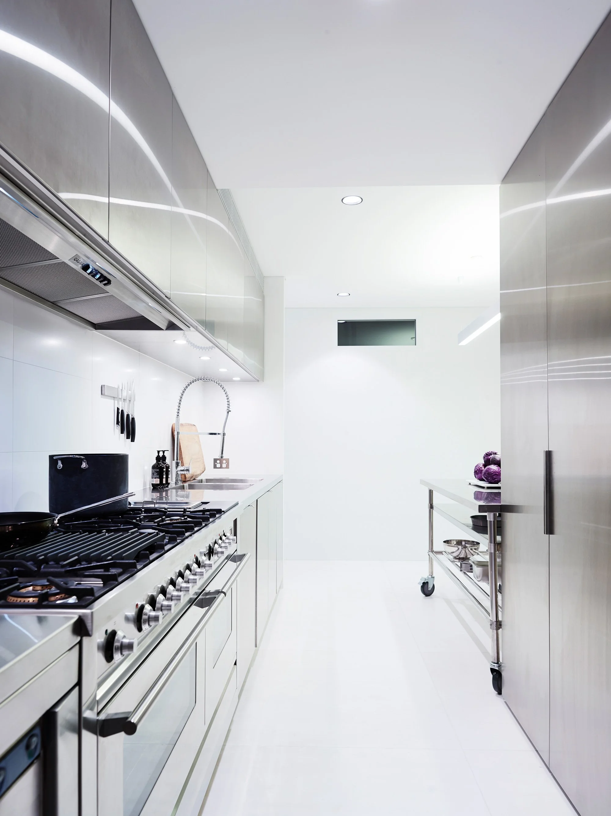 Modern, minimalistic kitchen with white walls and stainless steel appliances.