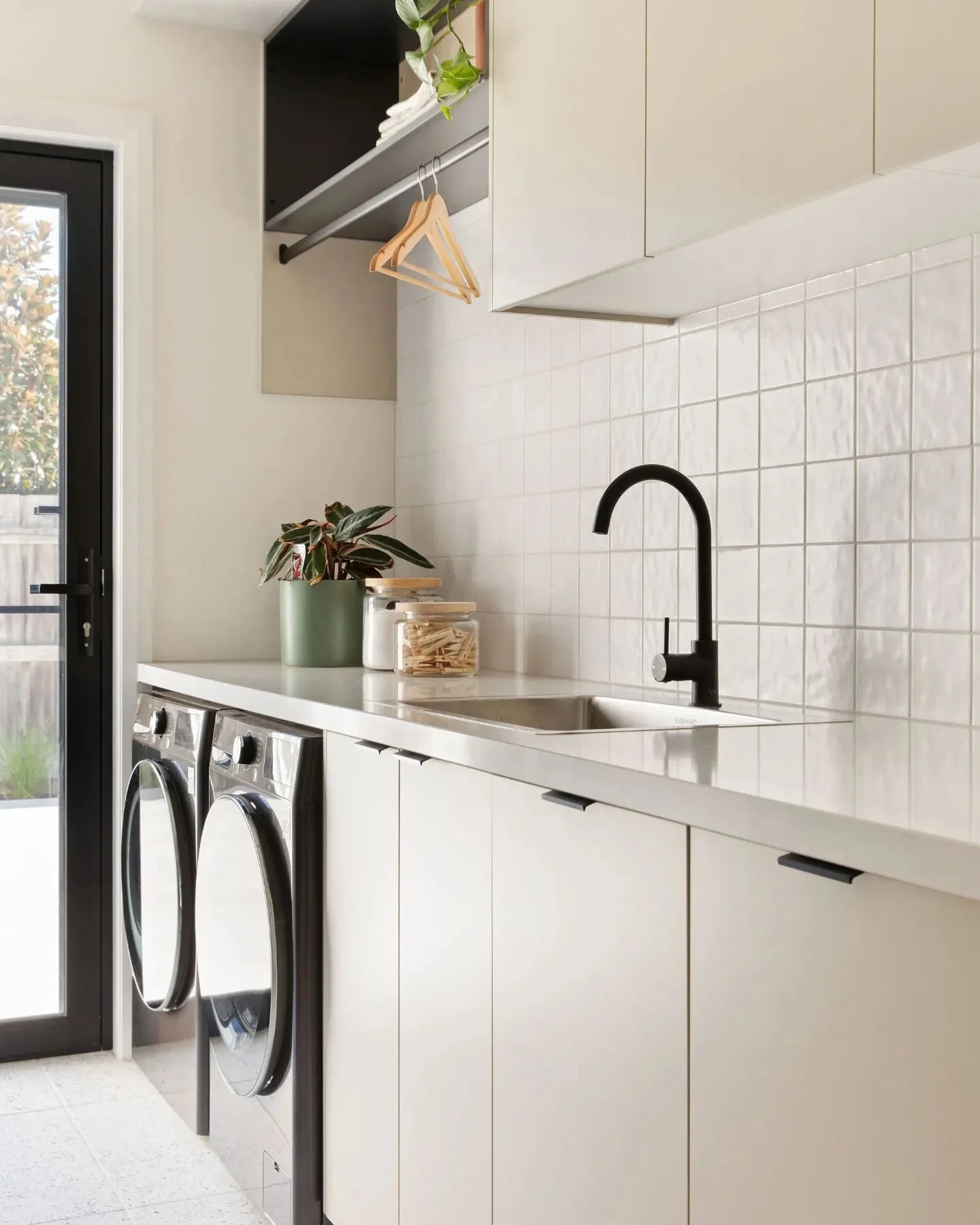 Laundry room essentials: a washer and dryer placed side by side, a hanging rod for clothes, and a cabinet storage space to house various household items. Straight forward as laundry rooms might be, you can still introduce design to this small space b