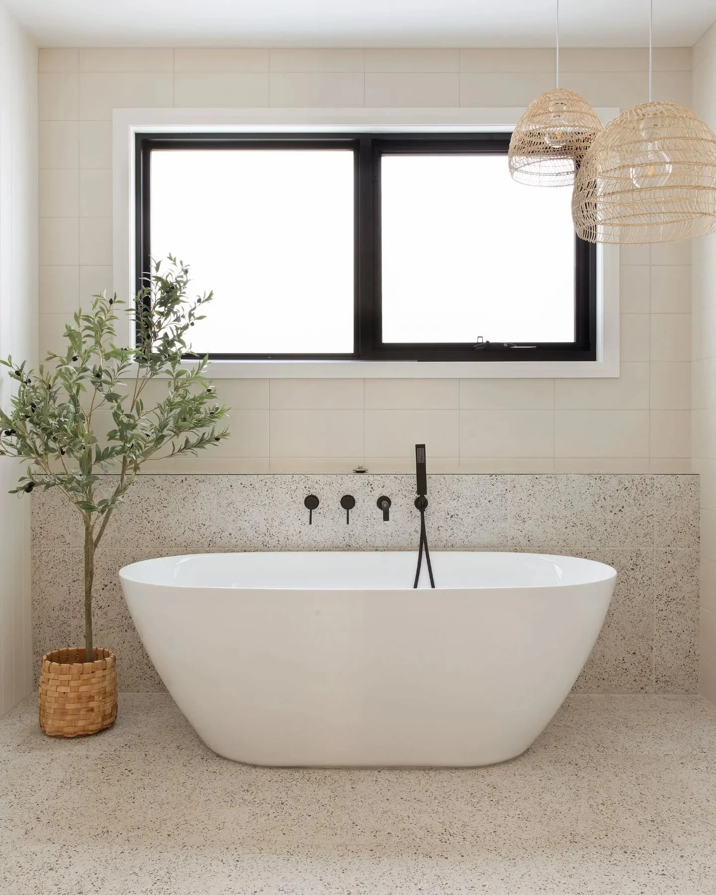 Terrazzo finishes, fixtures in black, and a pair of woven bamboo pendant lights make up this dreamy ensuite. Don&rsquo;t you think the freestanding bath just lures you to step in and relax? This is definitely the ensuite of your dreams. 
#DreamBathro