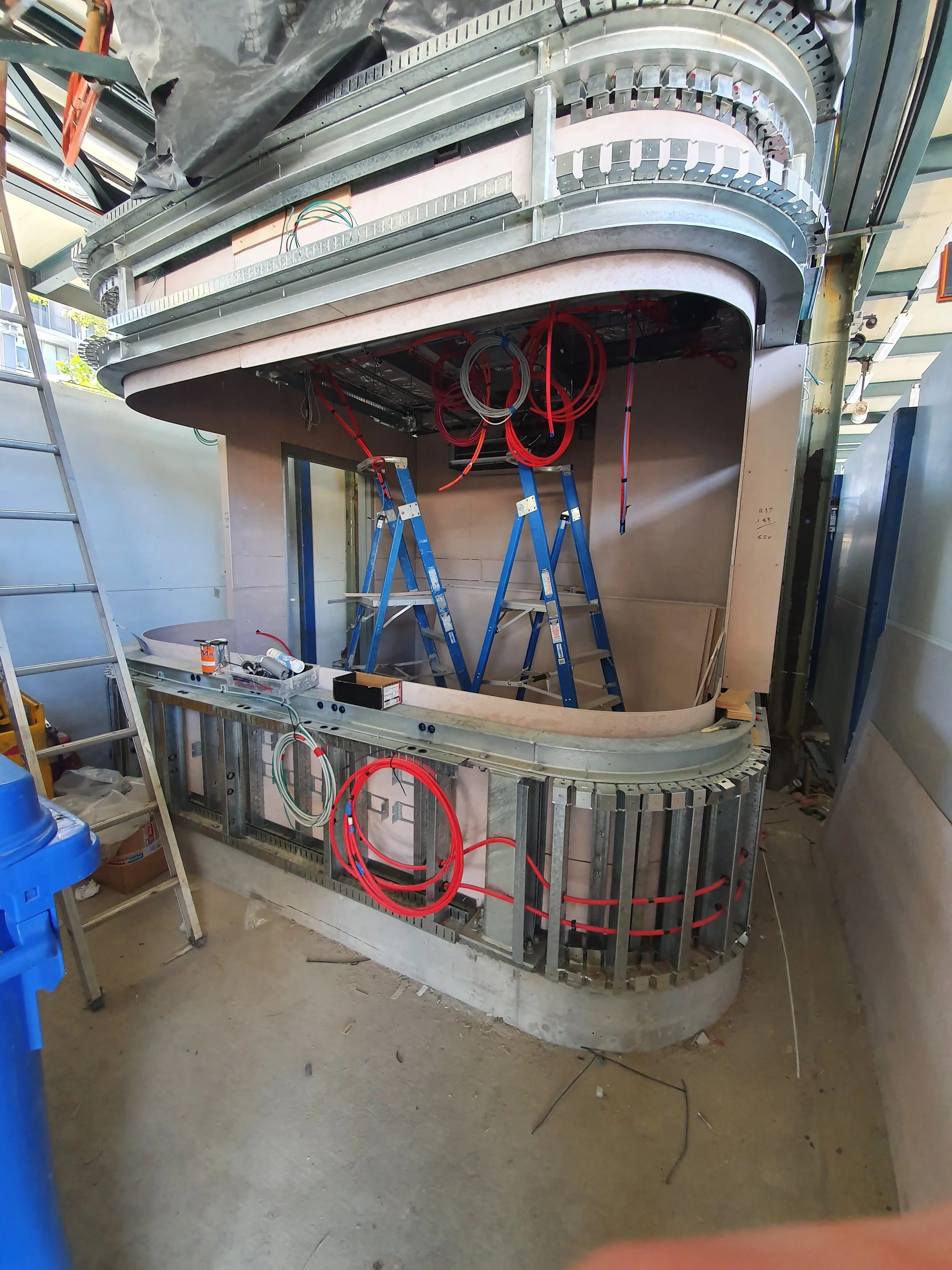Construction site with a partially built structure, ladders, and various tools and wires.