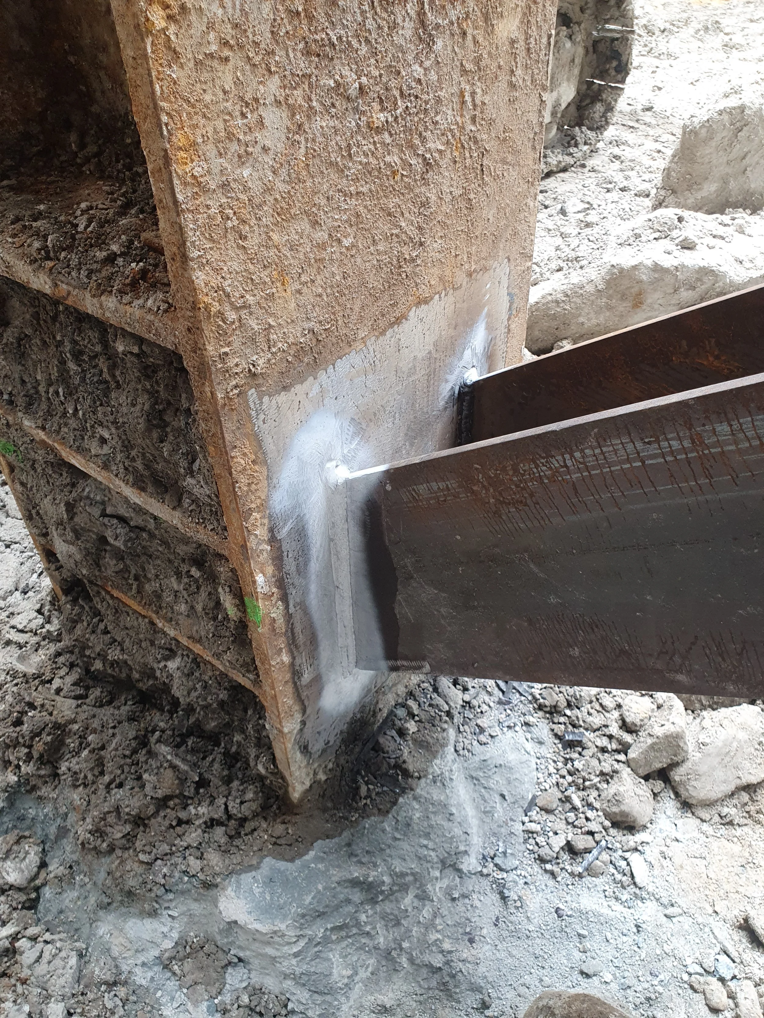 Welding a steel beam to a concrete foundation at a construction site.