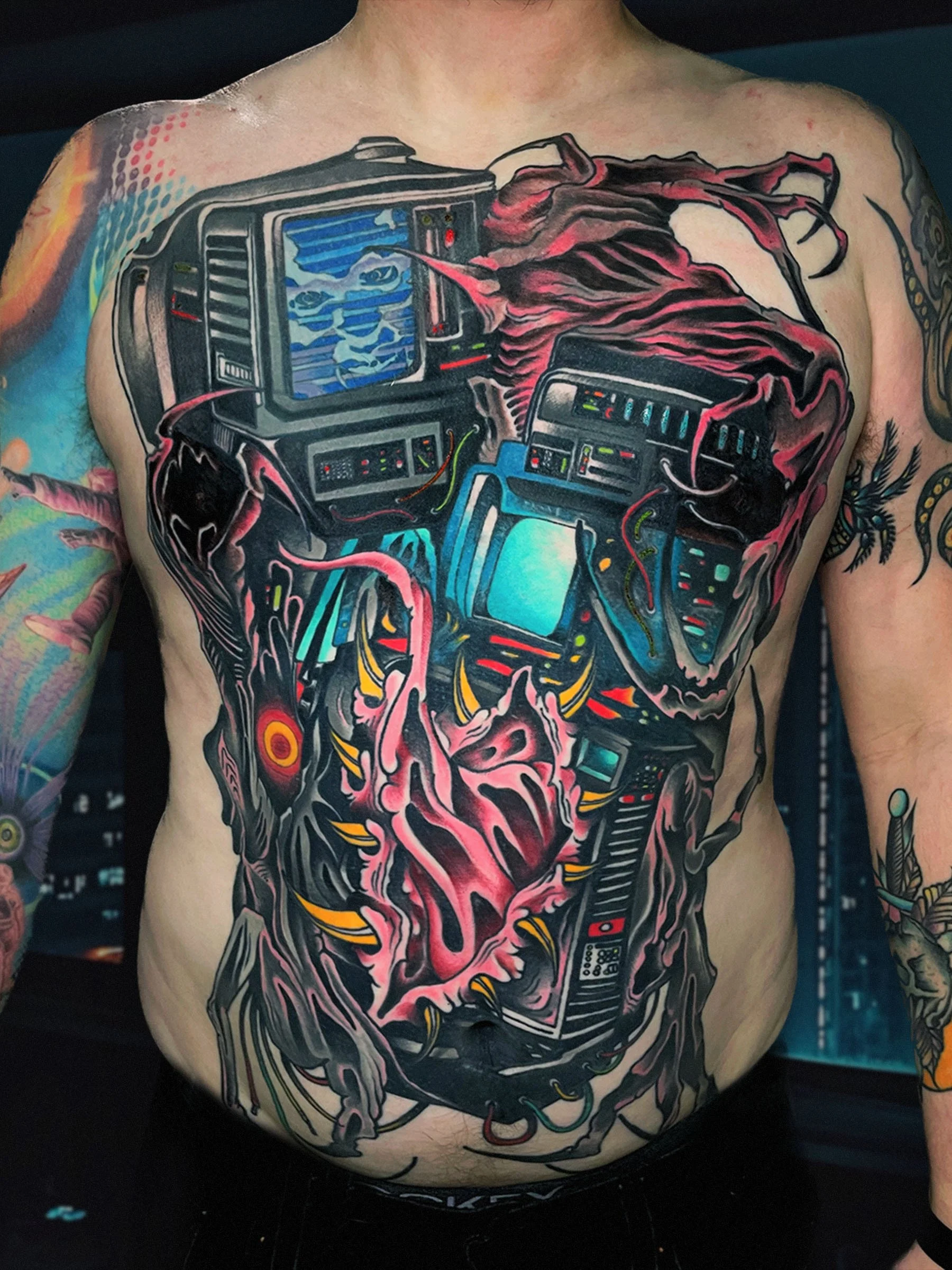 Large cyberpunk biomechanical chest tattoo with organic mutation and screens, tattooed by Shane Klos in Evansville, Indiana.