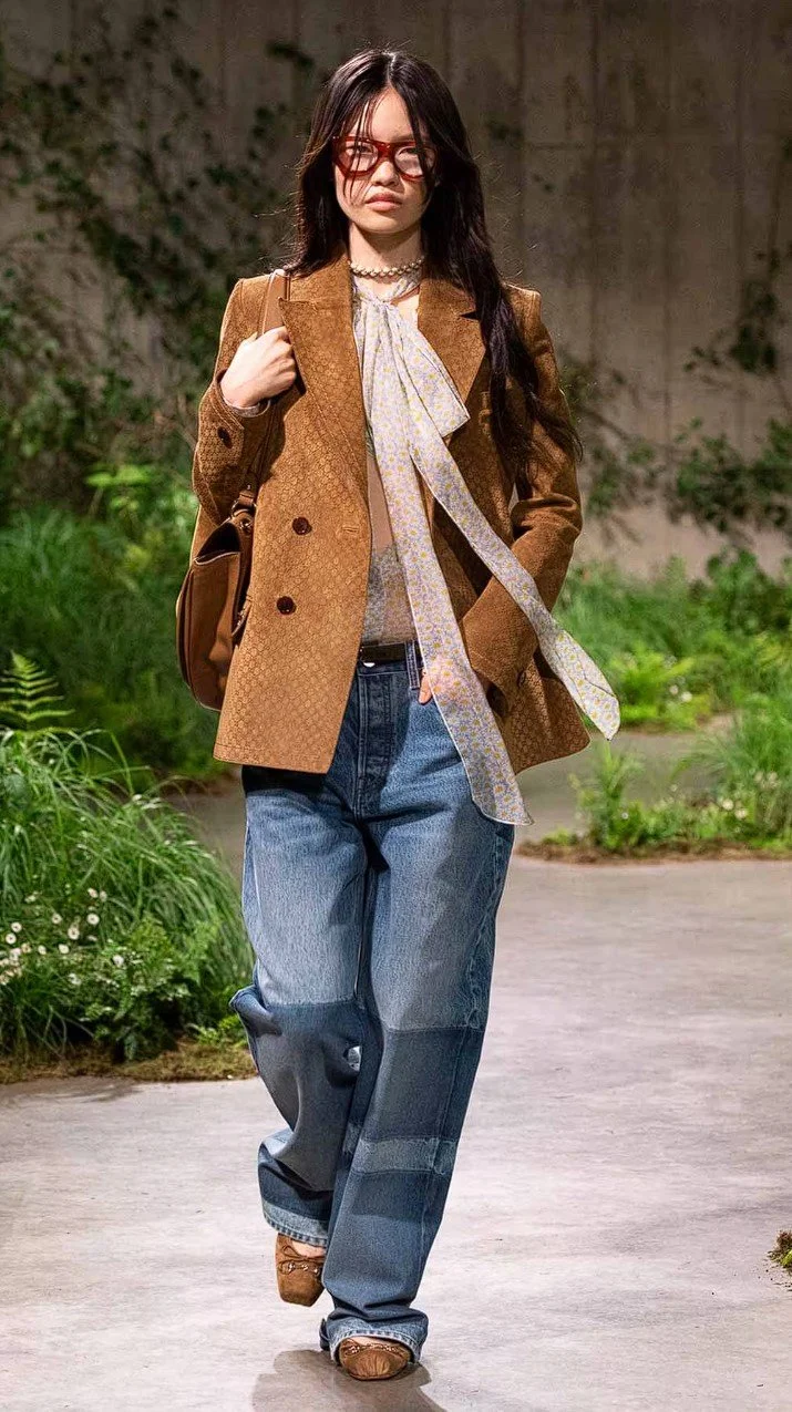 look-1-from-the-gucci-cruise-2025-collection-featuring-a-model-wearing-baggy-jeans-and-a-suede-brown-jacket.jpg