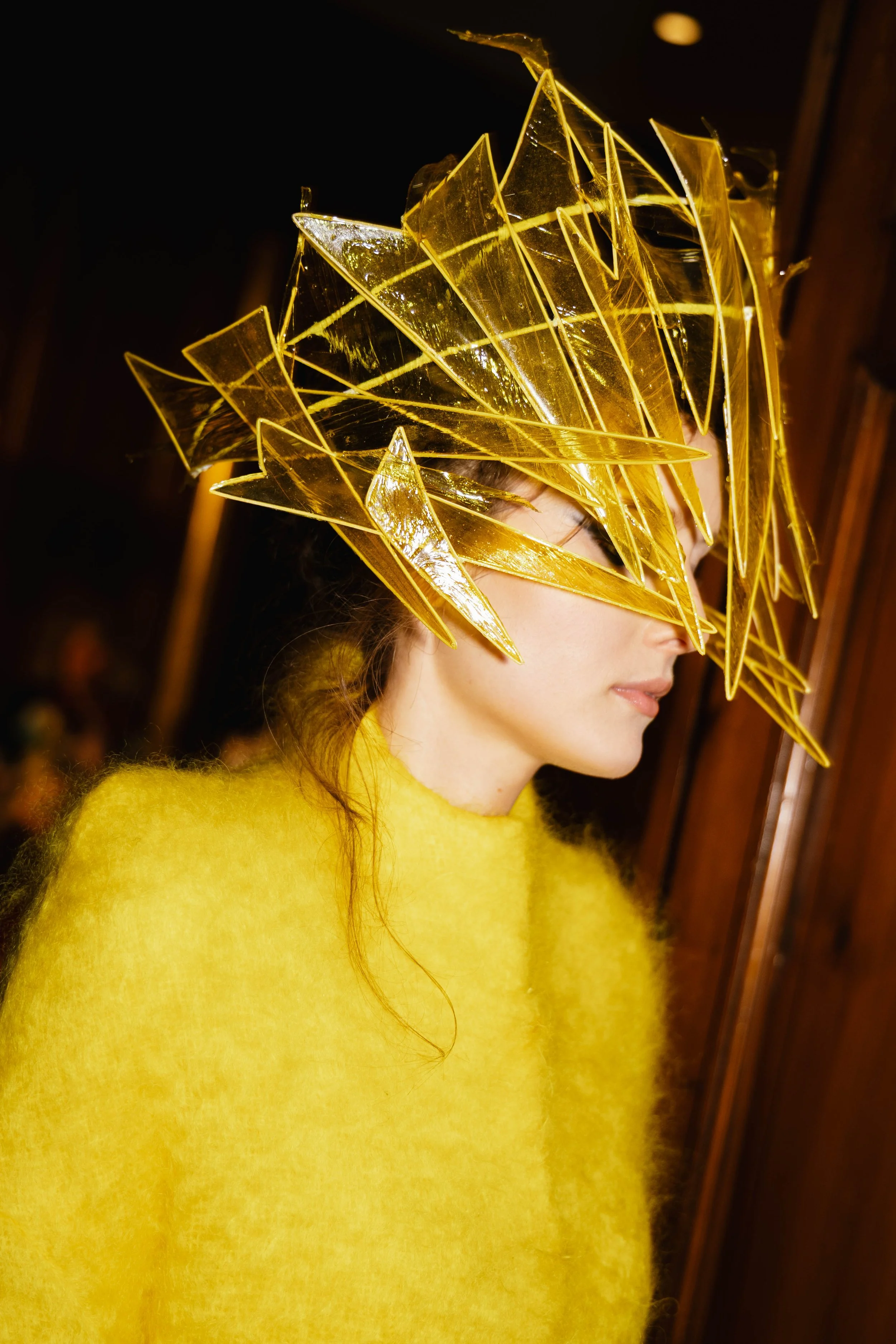 A close up of the model at the Genaro Rivas show wearing a yellow dress paired with a yellow mask resembling shattered glass