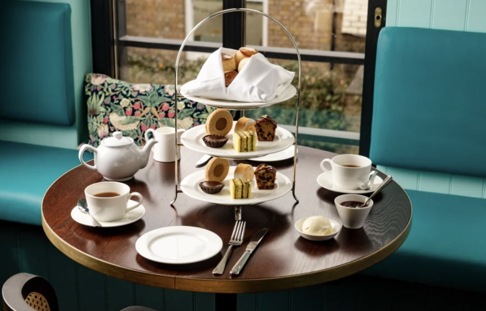 Afternoon tea table setup at Bread Ahead Tea House Belgravia London with finger sandwiches scones and patisserie on tiered stand