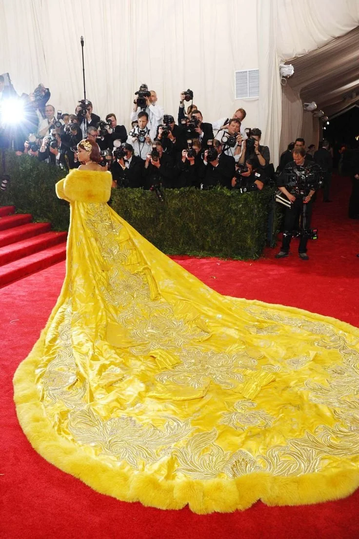 Rihanna wearing a dramatic yellow Guo Pei cape at the 2015 Met Gala