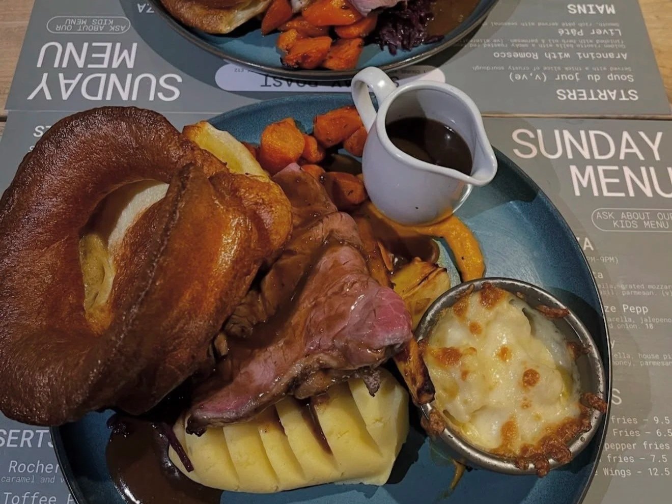 yorkies, cauliflower cheese, mash, beef, carrots gravy on a plate