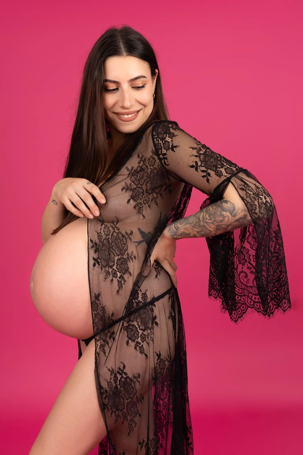 Femme enceinte sur fond rose en dentelle noire