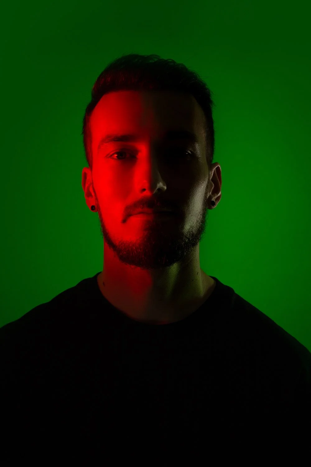 Homme de face, visage en lumière rouge, arrière plan éclairé en vert