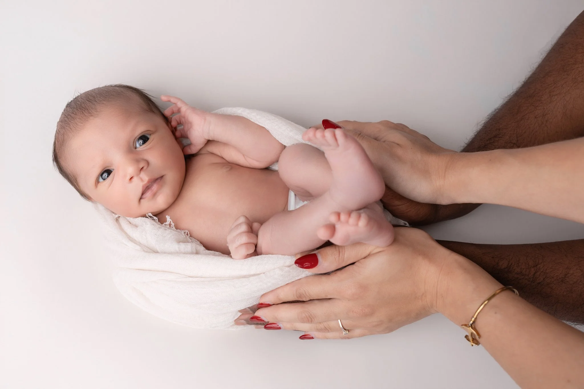 Séance photo naissance Yvelines - bébé en cocon entre les mains des parents