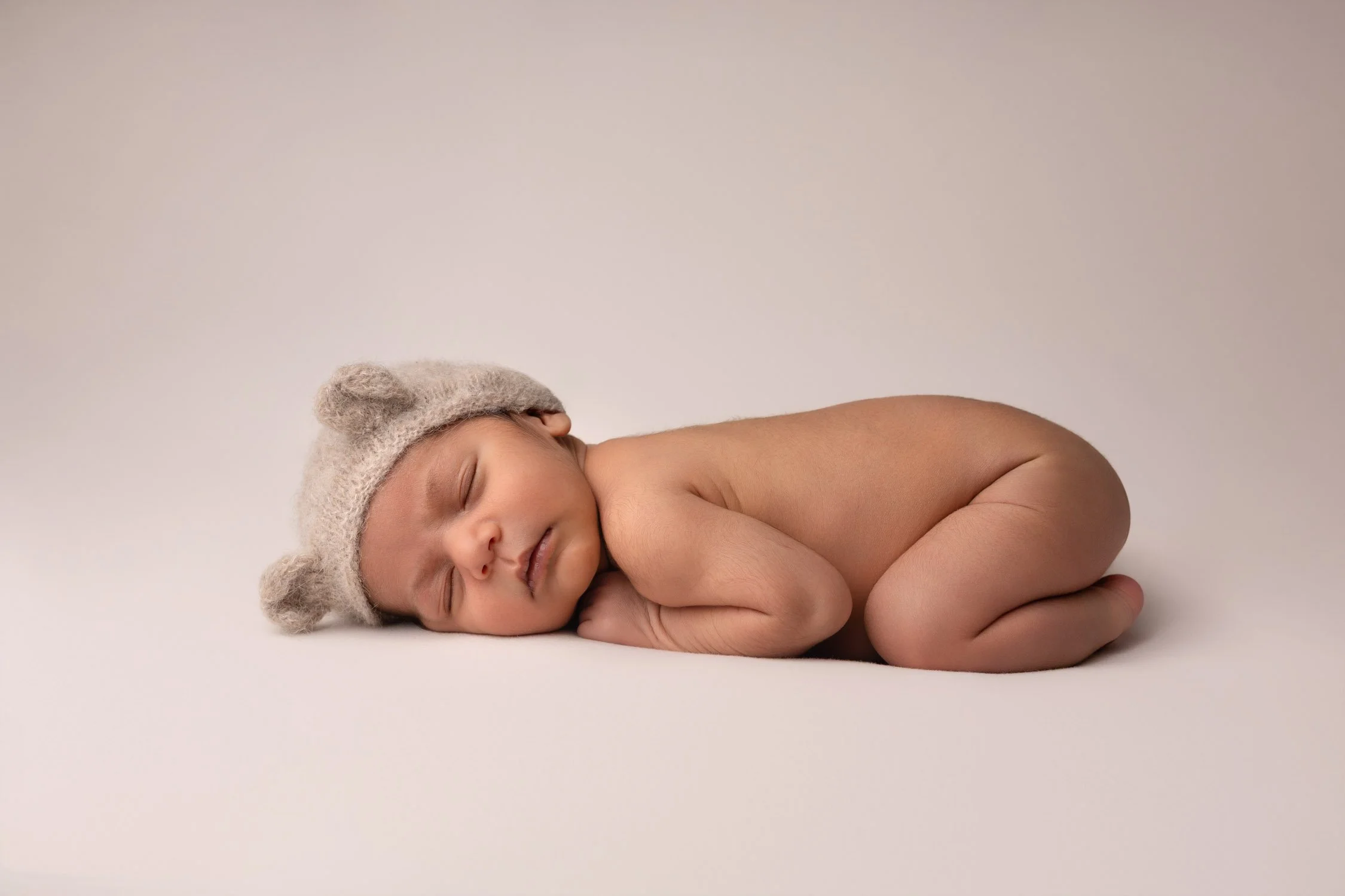 Séance photo naissance Yvelines - bébé endormi sur le ventre bonnet ourson