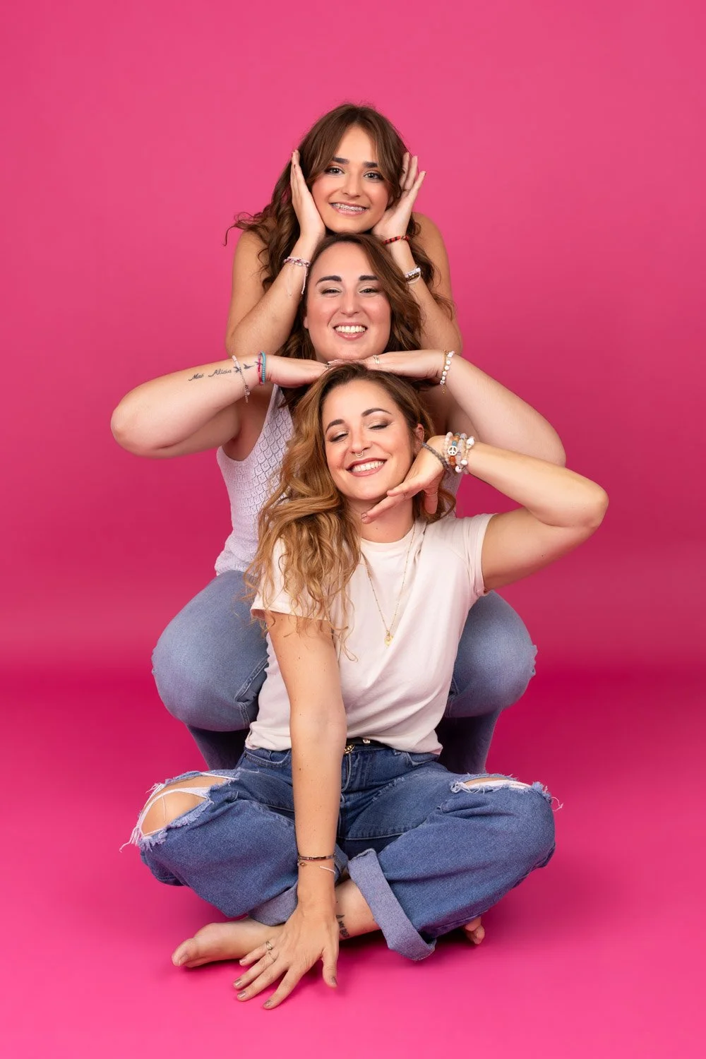 3 filles l'une au dessus de l'autre en jean sur fond rose