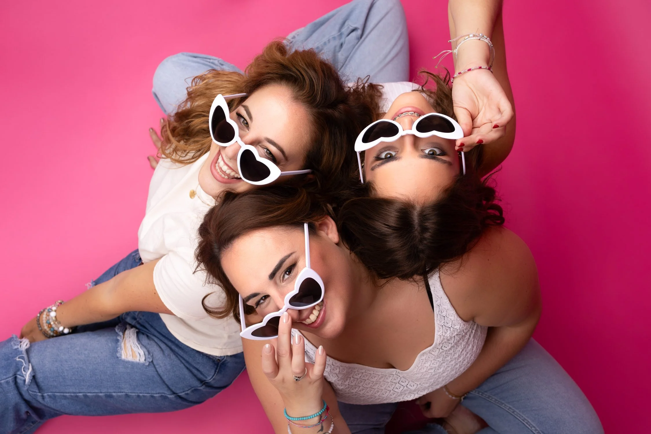 3 filles heureuse rigolant sur fond rose avec leurs lunettes coeur 