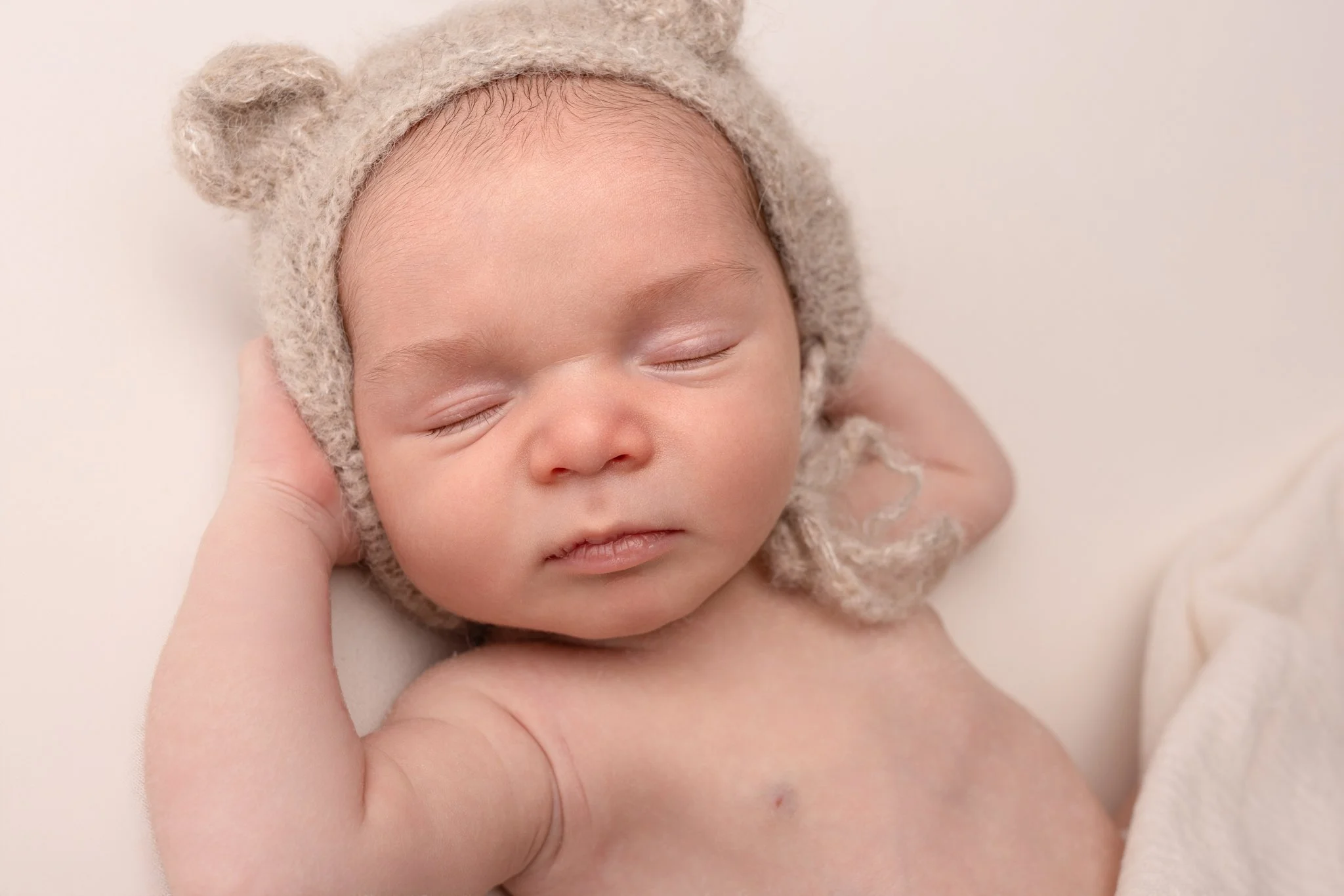 Séance photo naissance Yvelines - bébé endormi les mains derrière la tête 