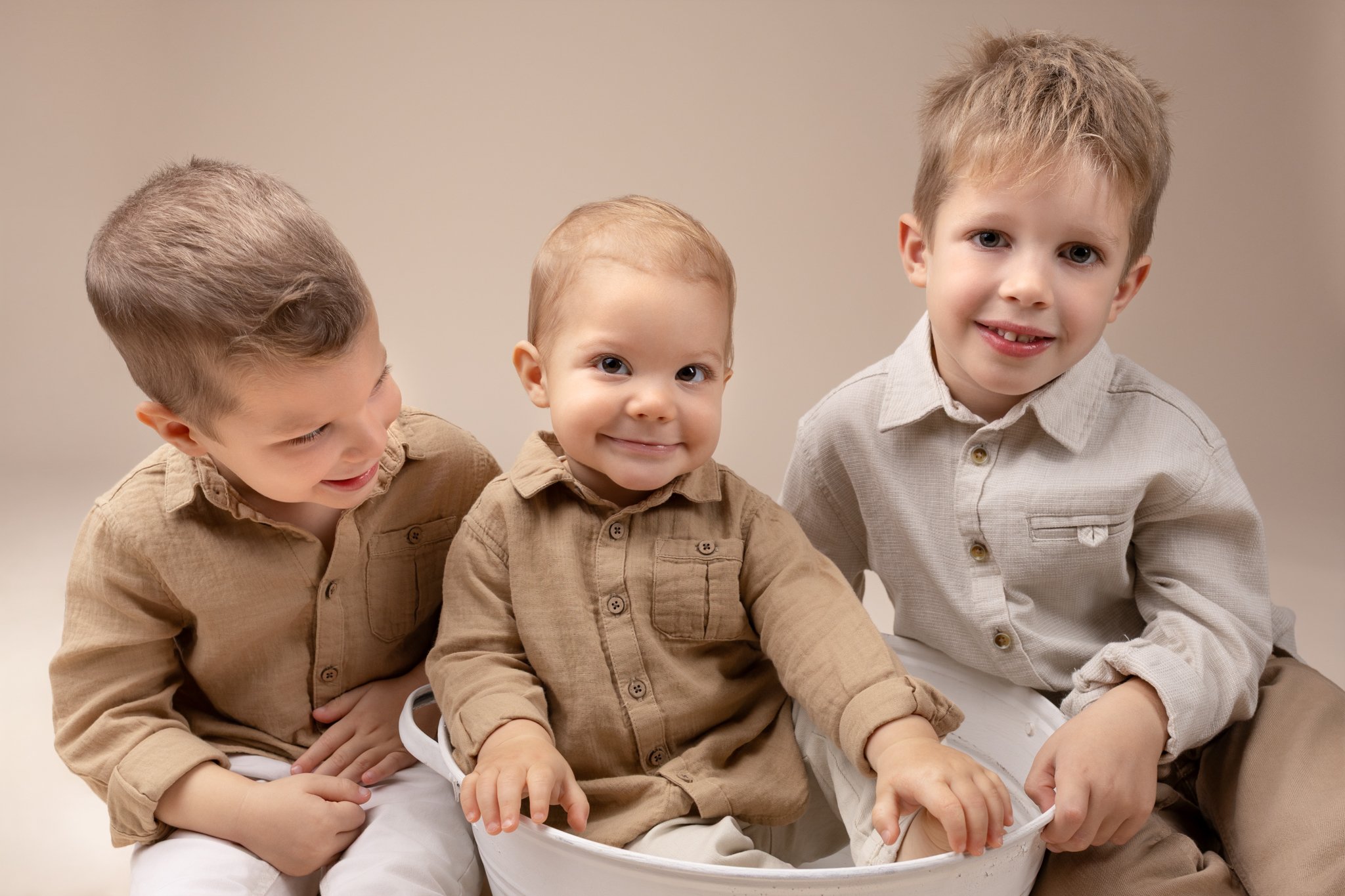 Séance photo famille Yvelines – 3 frères assis au sol fond beige
