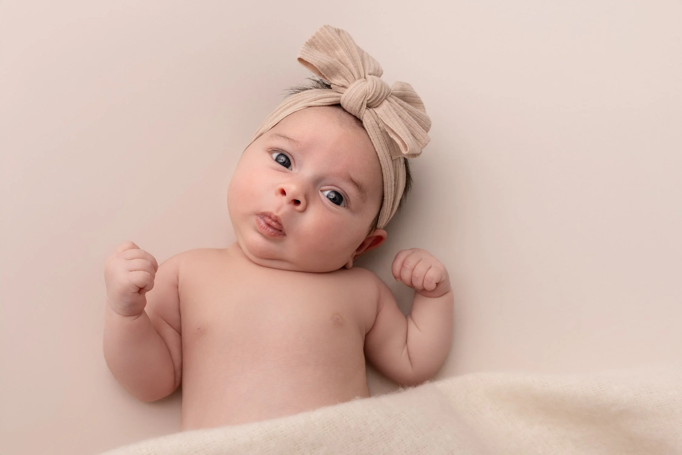 Séance photo naissance Yvelines - bébé à plat dos, éveillée avec headband 