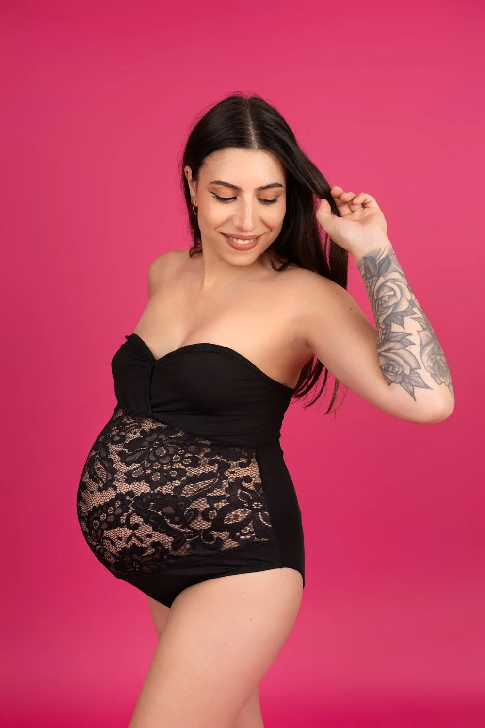 Femme enceinte sur fond rose en dentelle noire, intime et éclatant