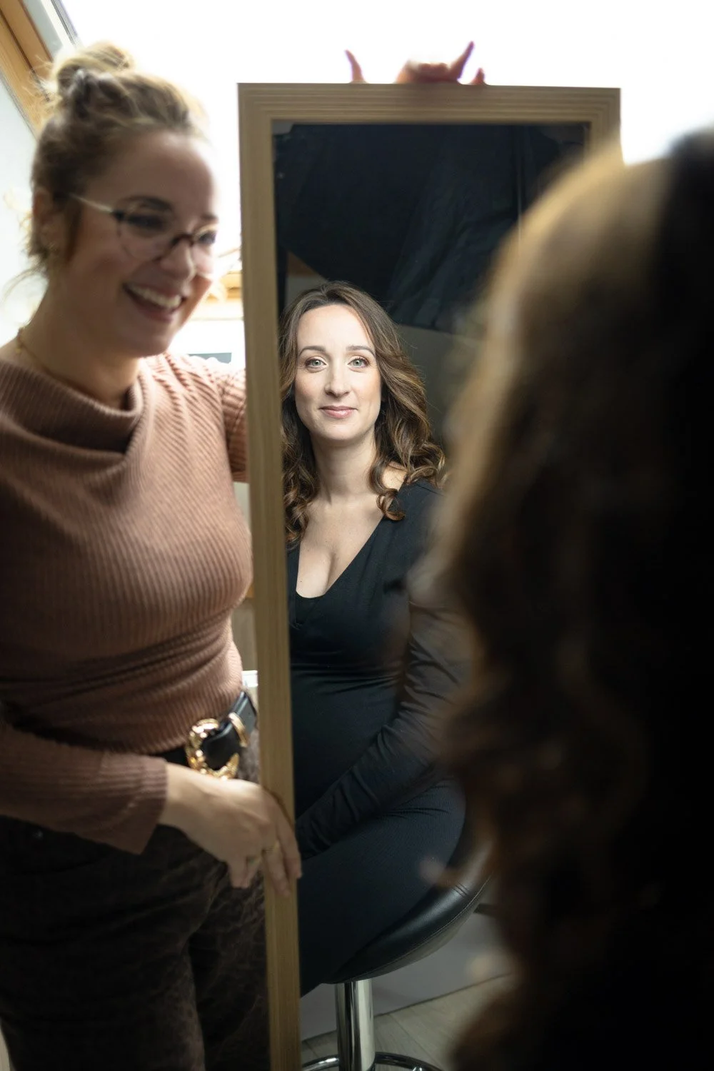 Femme qui se regarde dans le miroir une fois coiffée et maquillée