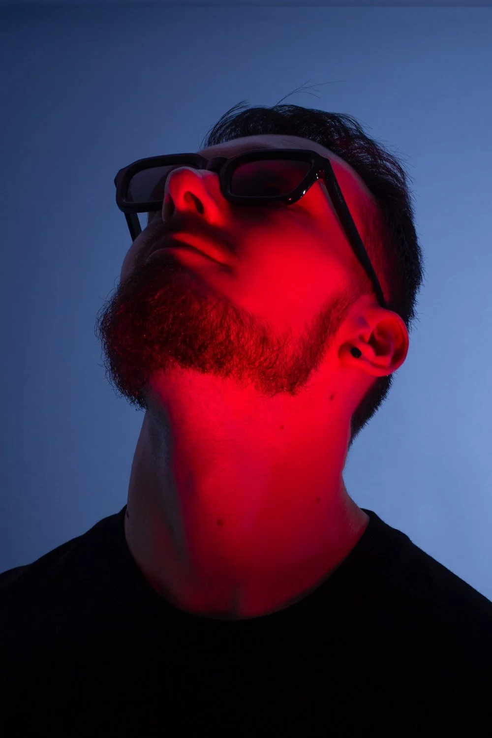 Homme regardant vers le haut, lumière rouge sur le visage, bleu à l'arrière plan