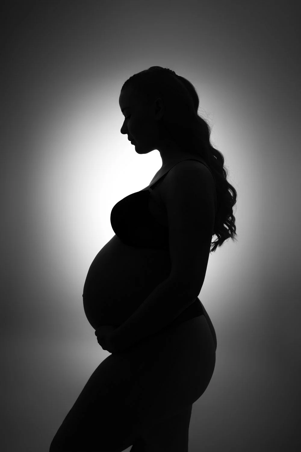 Séance photo grossesse Yvelines - future maman avec halo en fond, contre jour, noir et blanc, aperçu de la silhouette uniquement
