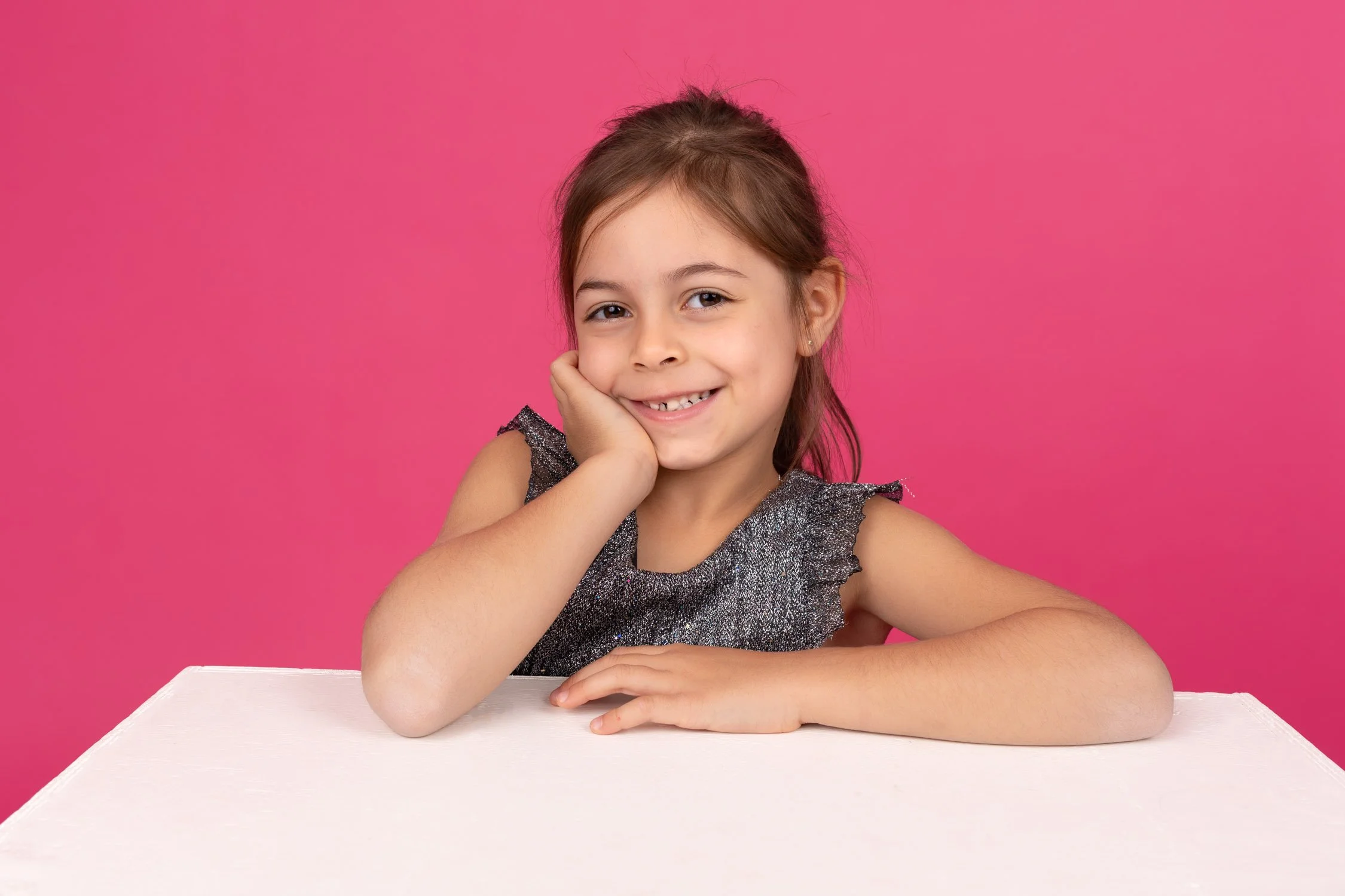 Petite fille souriante sur son cube avec le fond rose