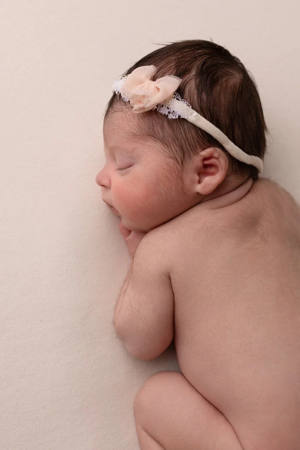 Séance photo naissance Yvelines - bébé vue de haut endormi avec headband fleuri 