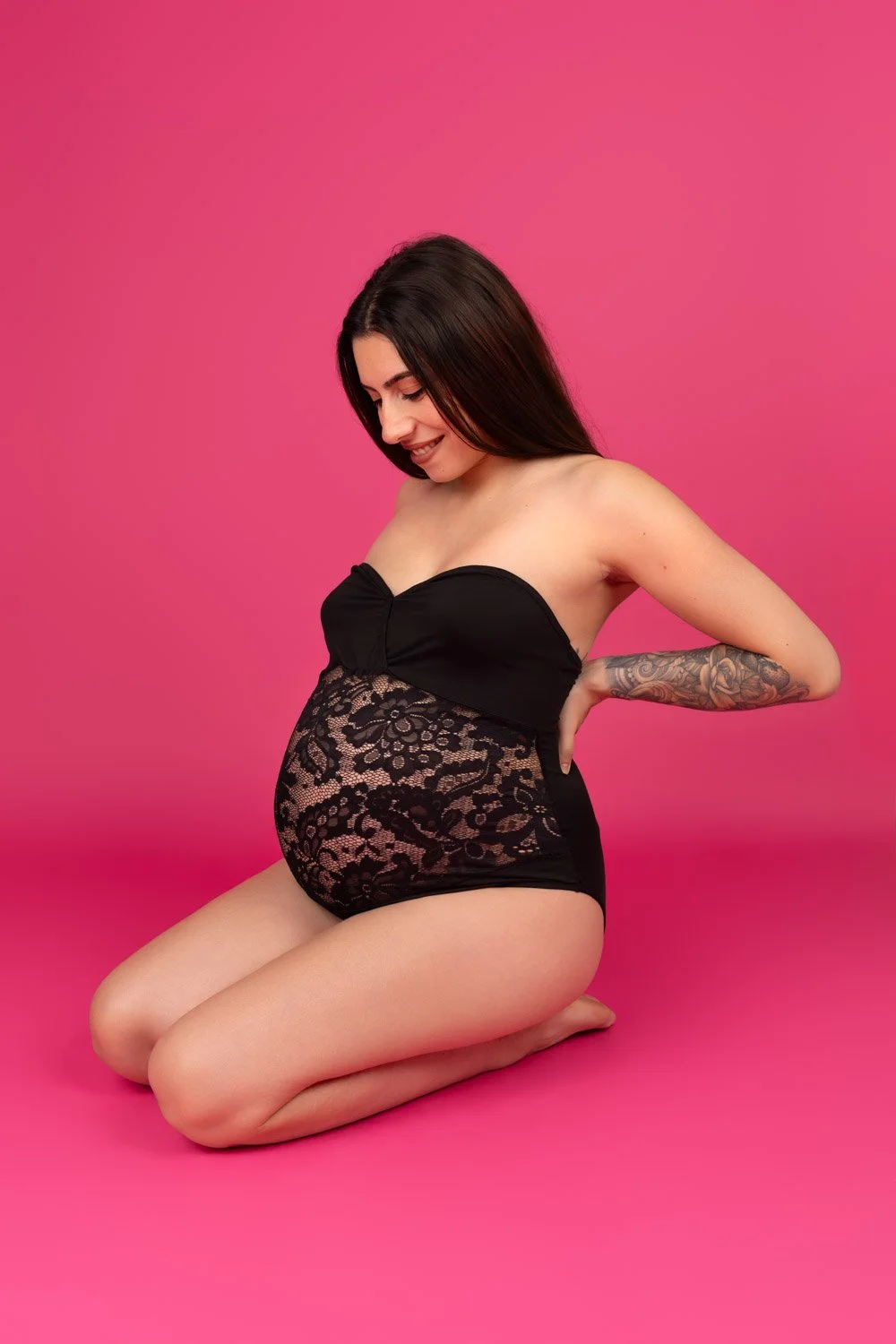 Femme enceinte dentelle noire sur fond rose