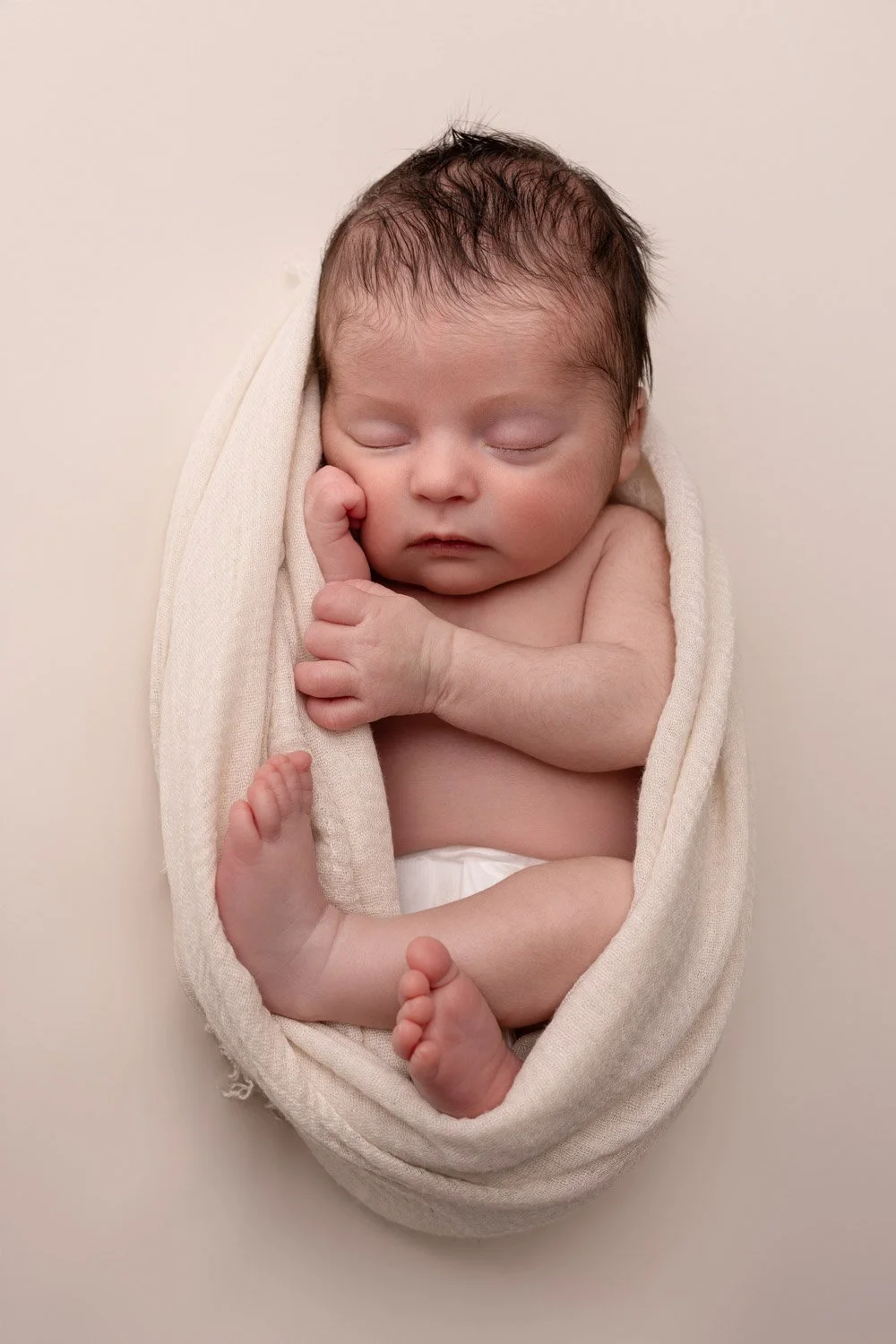 Séance photo naissance Yvelines - bébé endormi en cocon main sur le joue