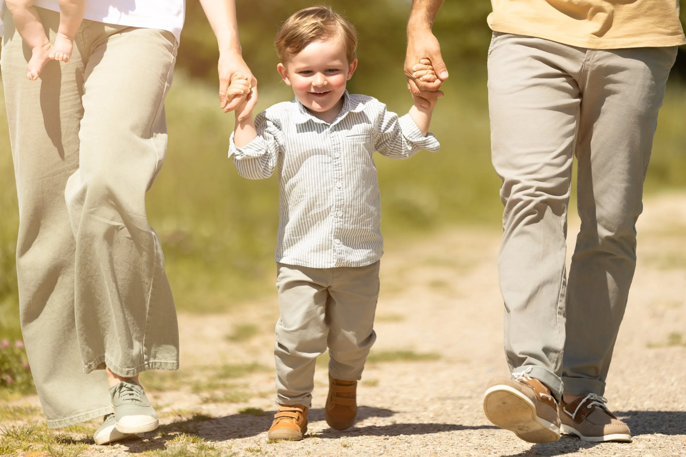 Séance photo famille en extérieur Yvelines – petit garçon marche en tenant les mains de ses parents