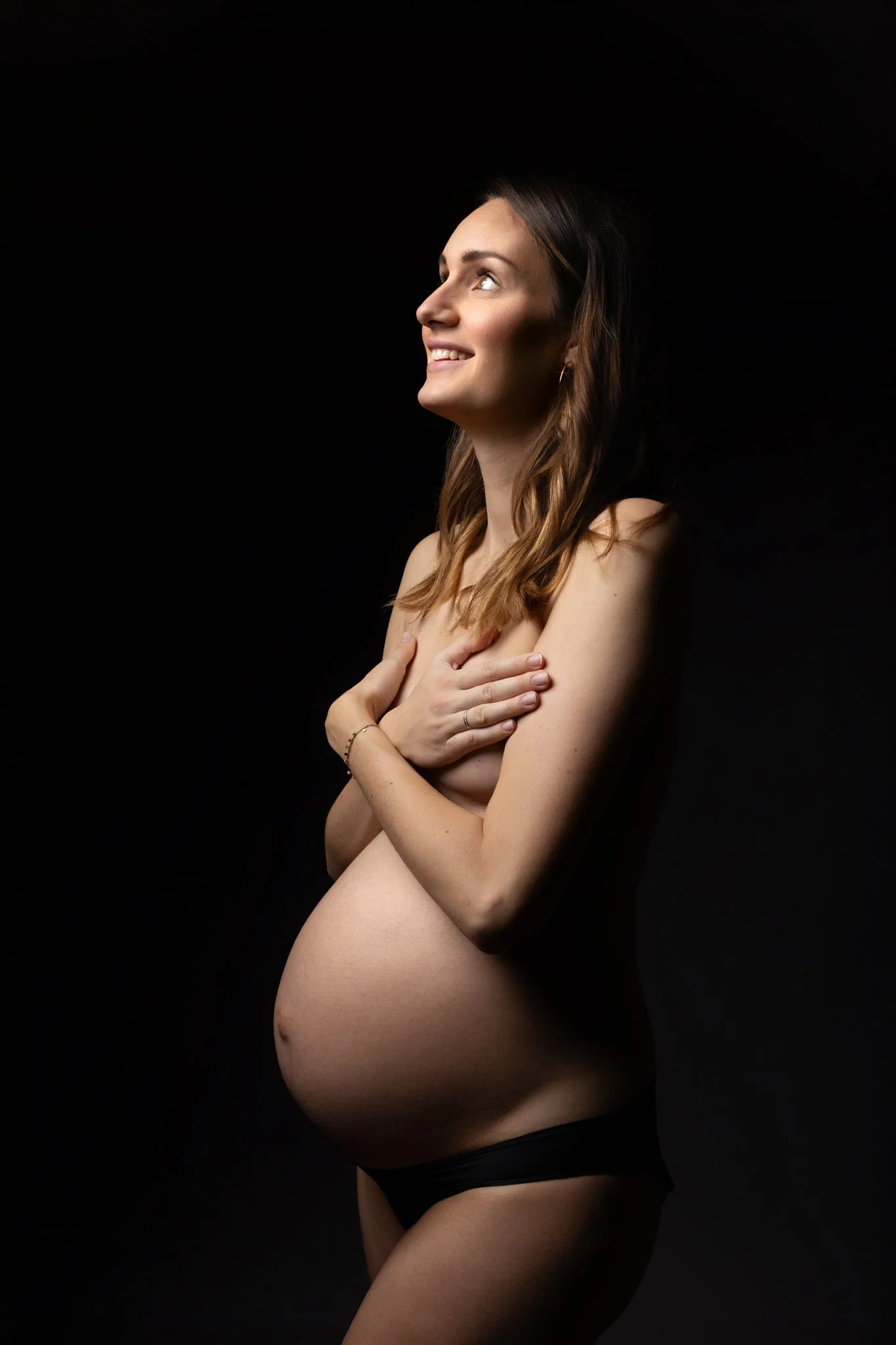 Séance photo grossesse Yvelines - future maman en clair obscur, mains cachant la poitrine, ventre nu