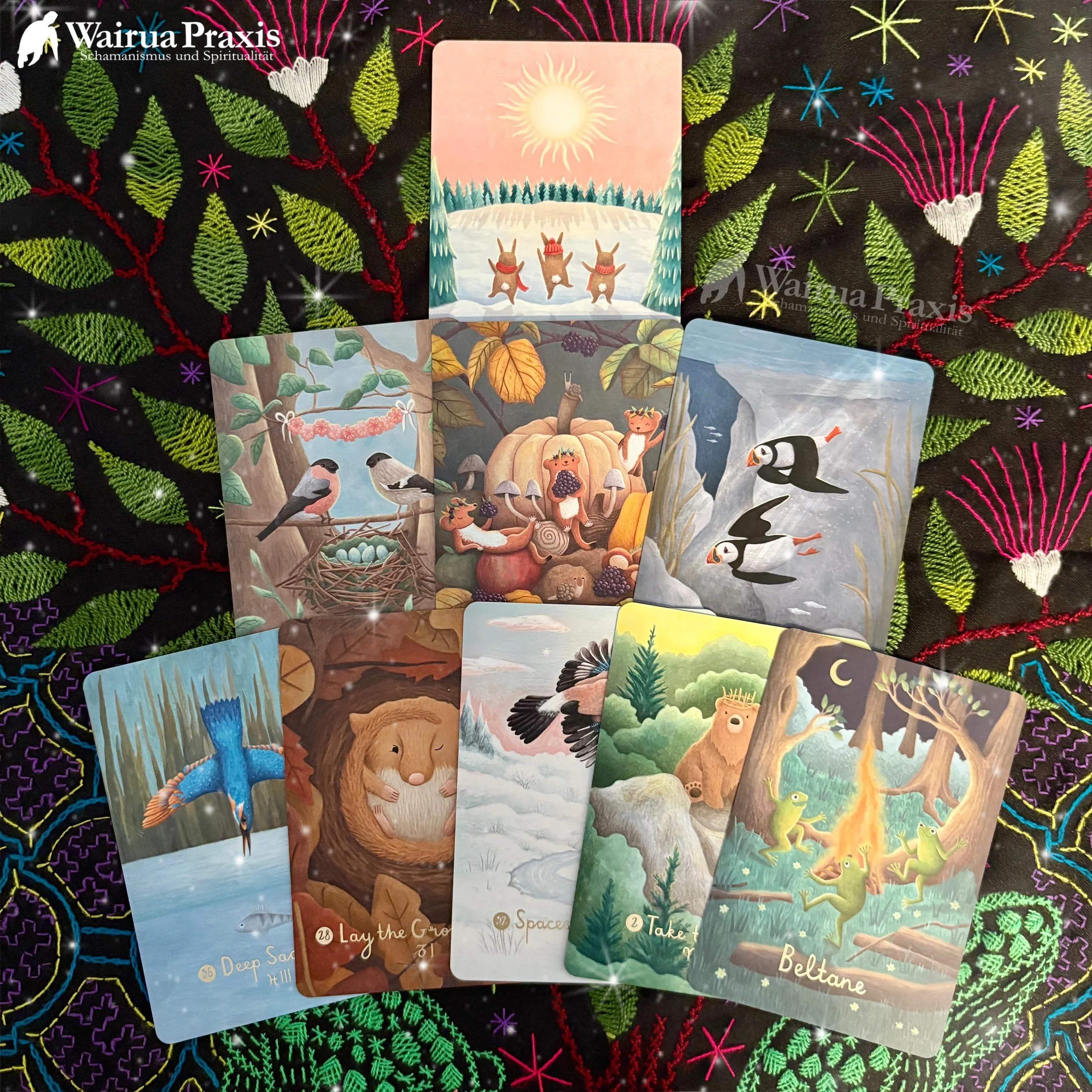 Verschiedene Tarotkarten mit Tieren, Monden und Naturmotiven, auf einem dekorativen, bunten Stickuntergrund