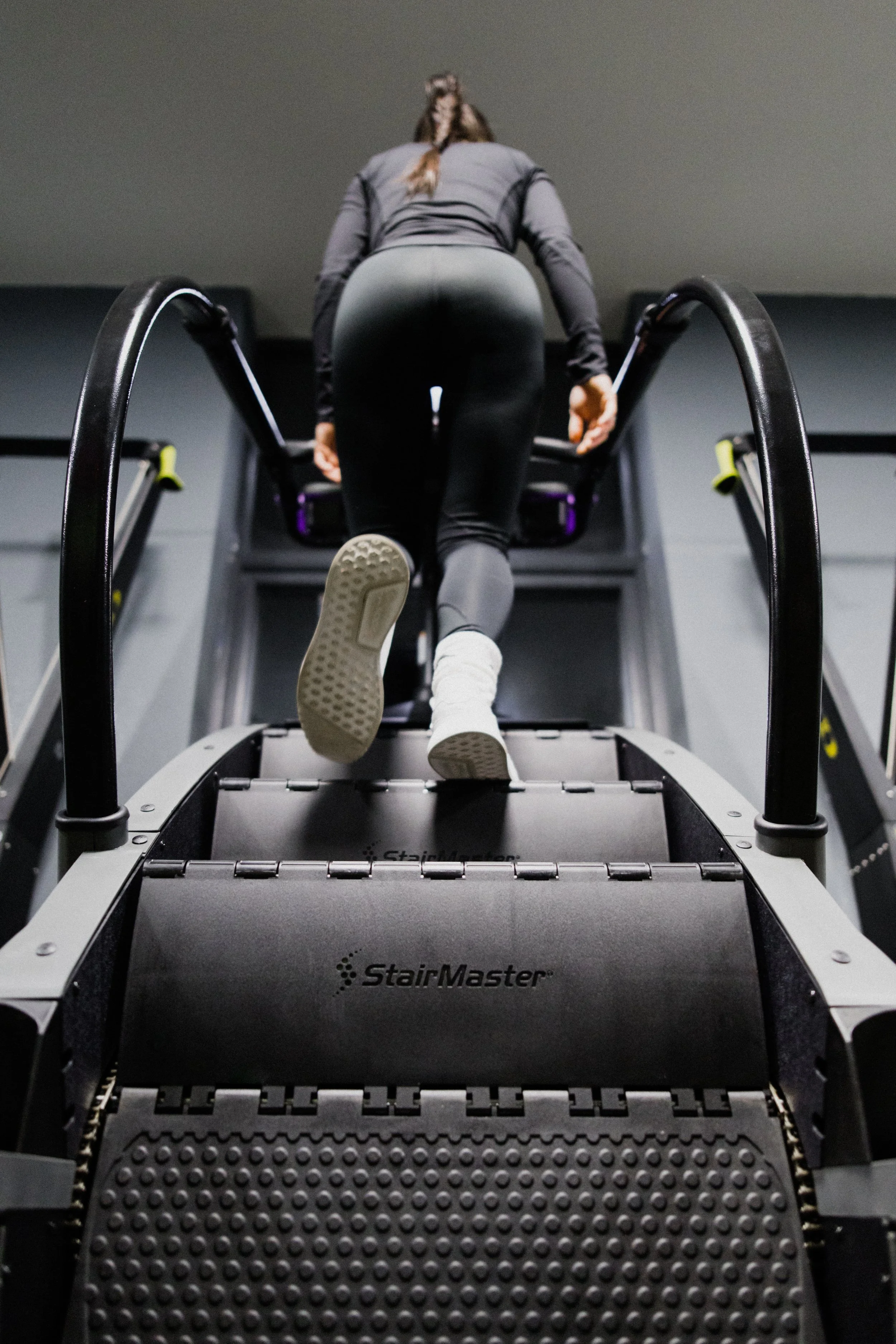 A woman in black gym clothing is walking o n a black StairMaster machine at Alpha Athletic gym in Newport.
