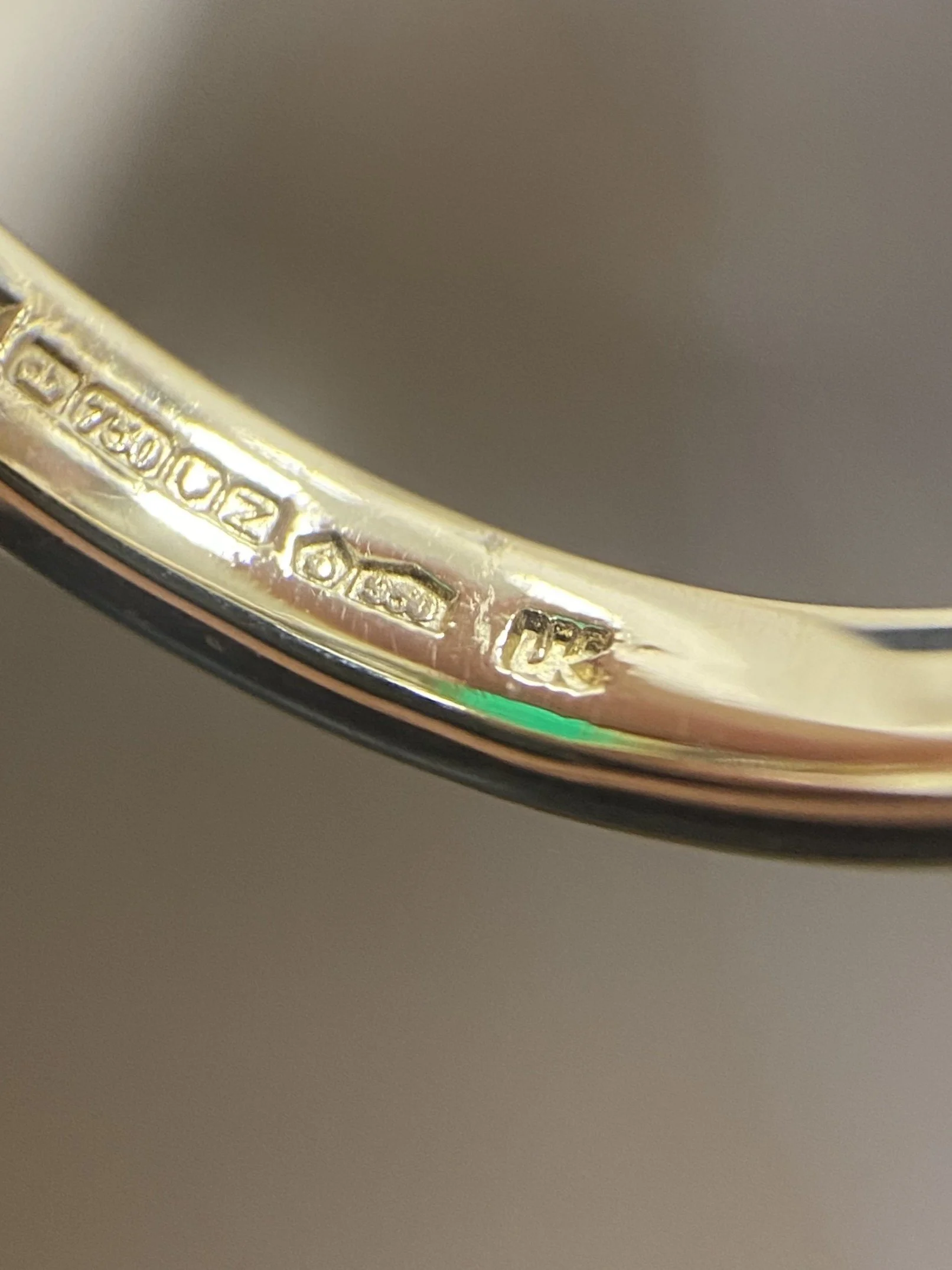 Close-up of a gold ring with engraved hallmarks and stamps, including '750,' indicating 18-karat gold.