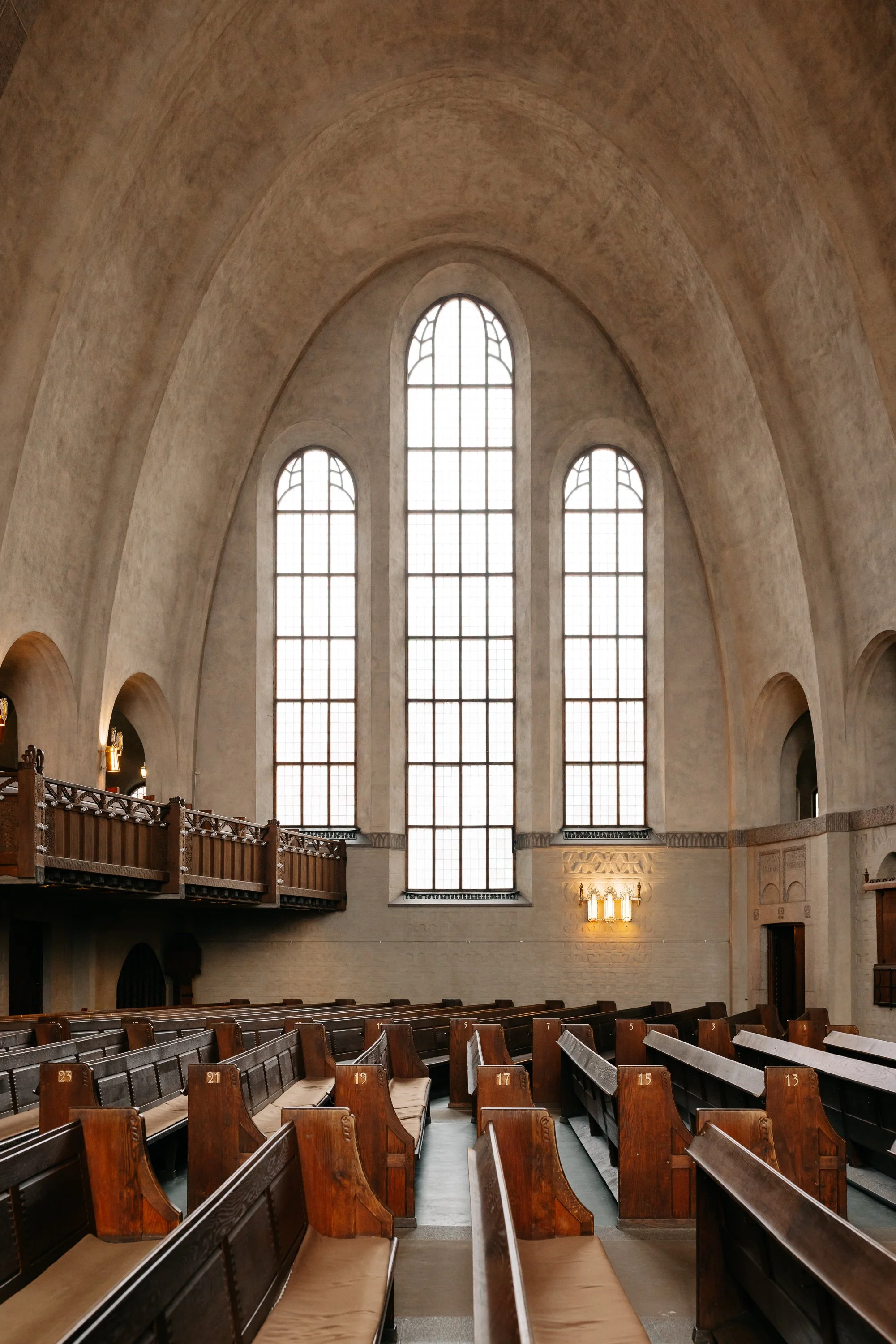 Interiör av en kyrka med trähörnssitsar och stora fönster, Engelbrektskyrkan i Stockholm.