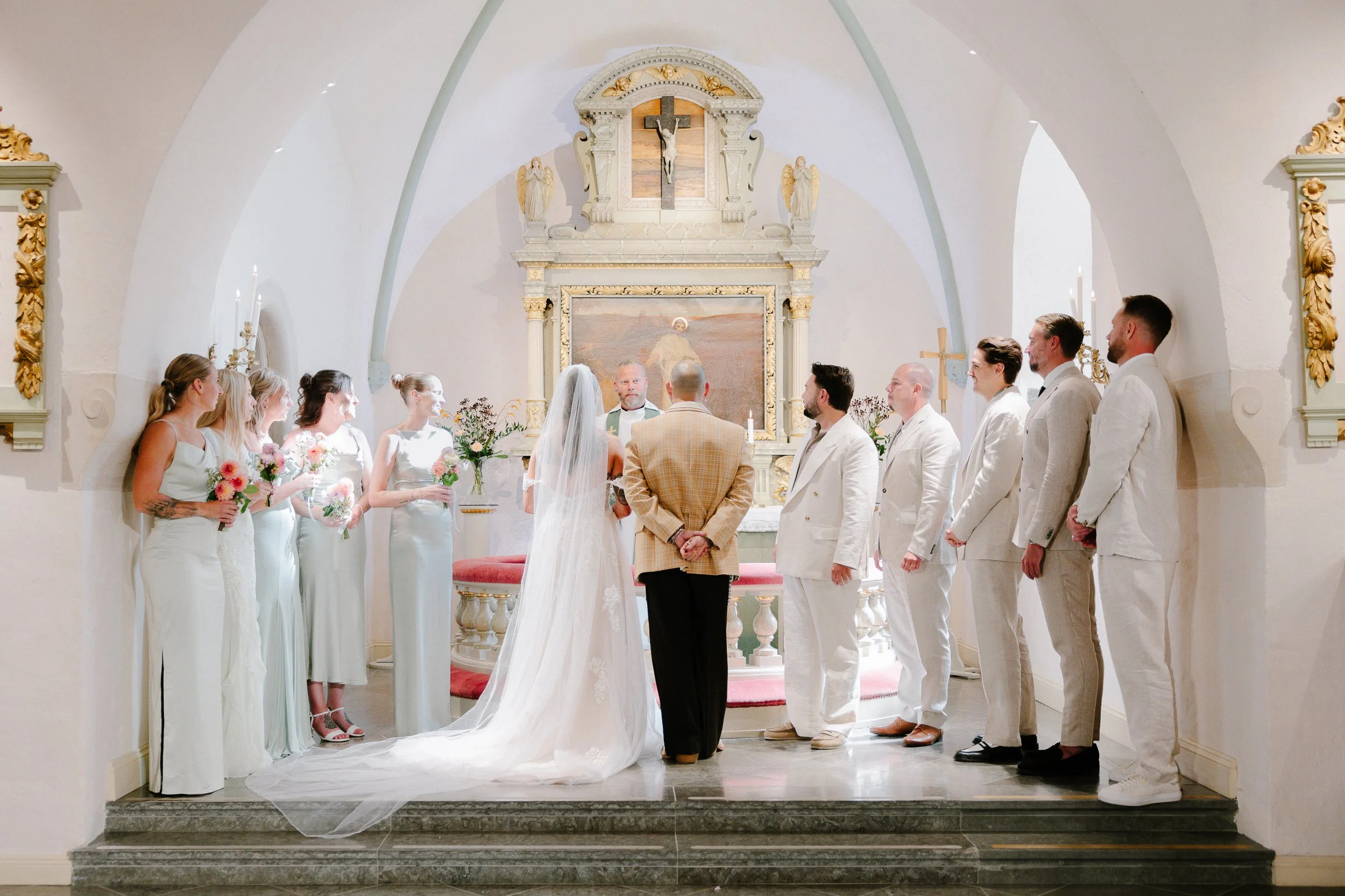 En kyrklig vigsel ceremoni med en brud i vit klänning och ett brudfrämling är framför en präst. Av Sofia Wilhelmina bröllopsfotograf i Stockholm.