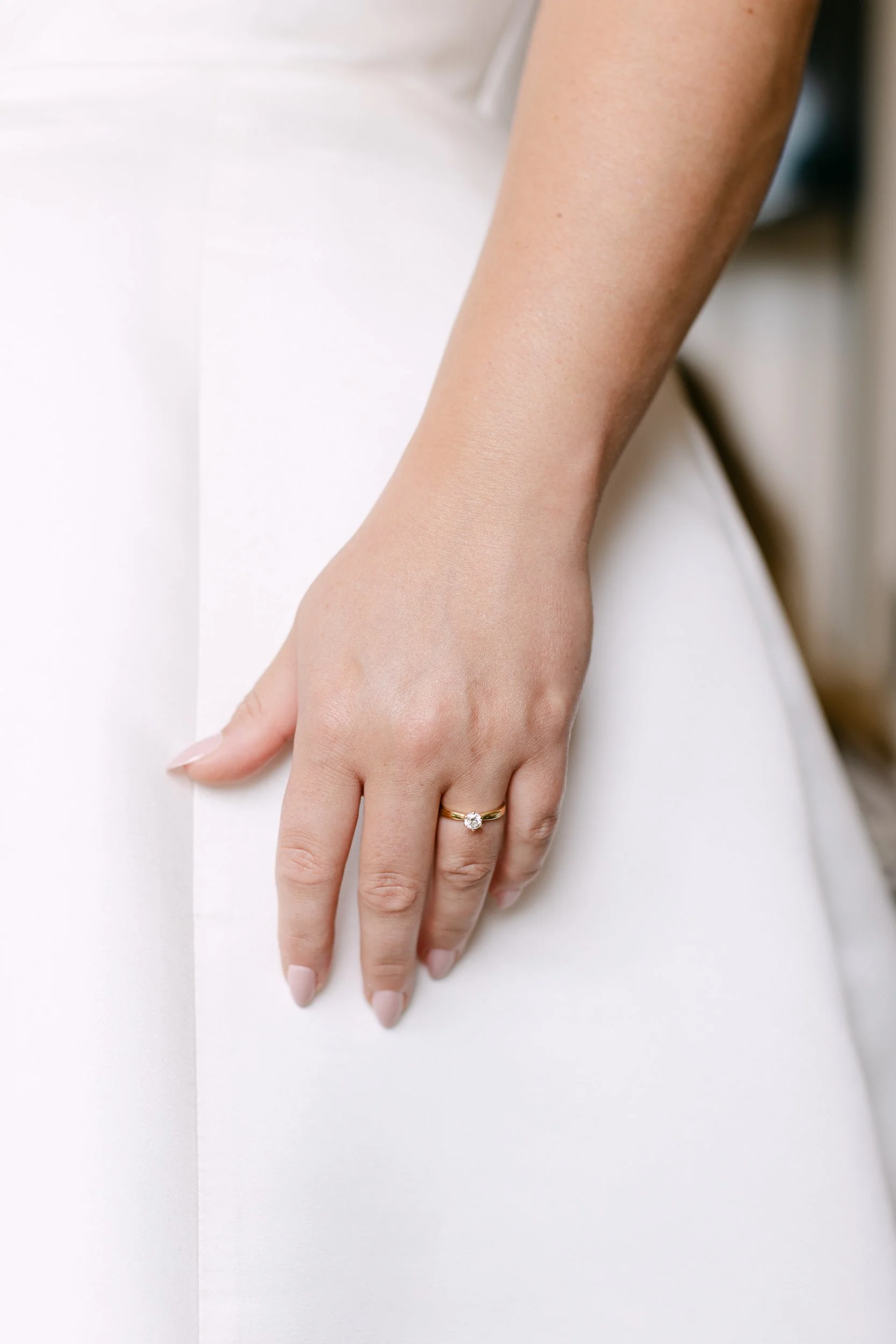 Närbild av två händer, ett finger har en diamantoformad ring, mot en vit bakgrund.